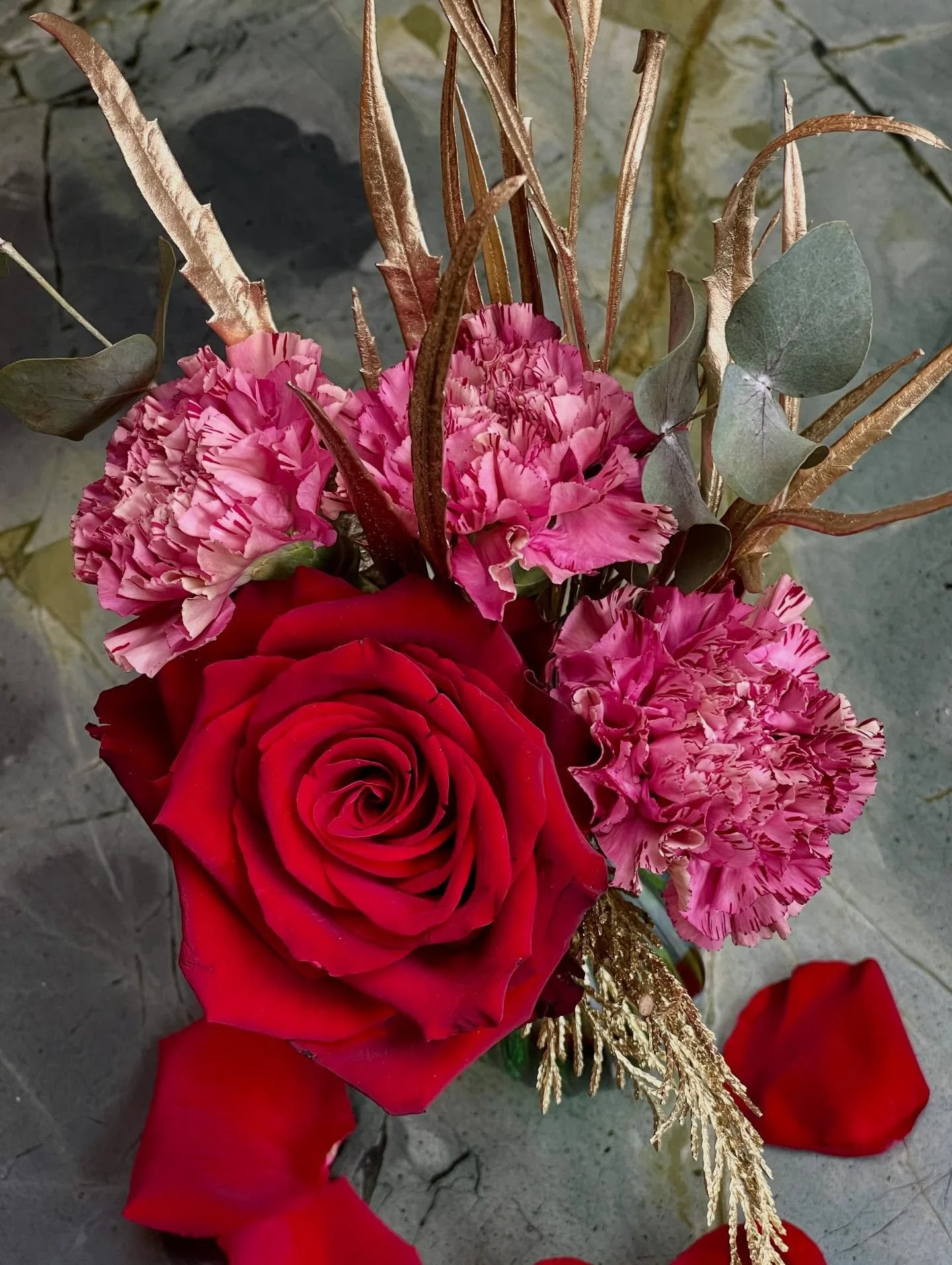 The St-ROSE Golden Blush Bud-Vase Arrangement &mdash; where deep crimson roses meet soft blush carnations, finished with a whisper of gilded foliage. A couture balance of romance and radiance, designed to glow softly in winter light and elevate every