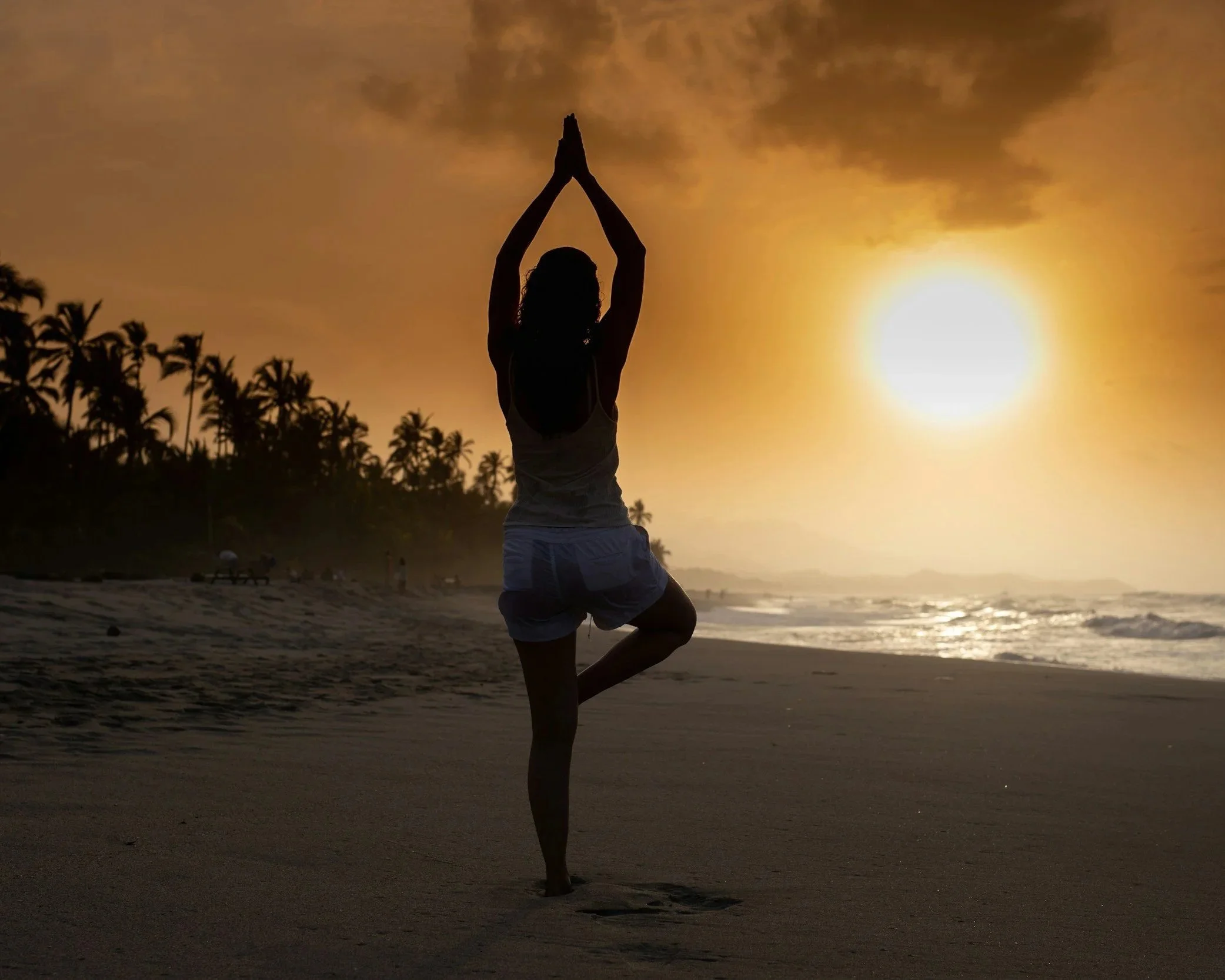 Woman practicing yoga at sunset, symbolizing nervous system calming rituals to quiet mental static.