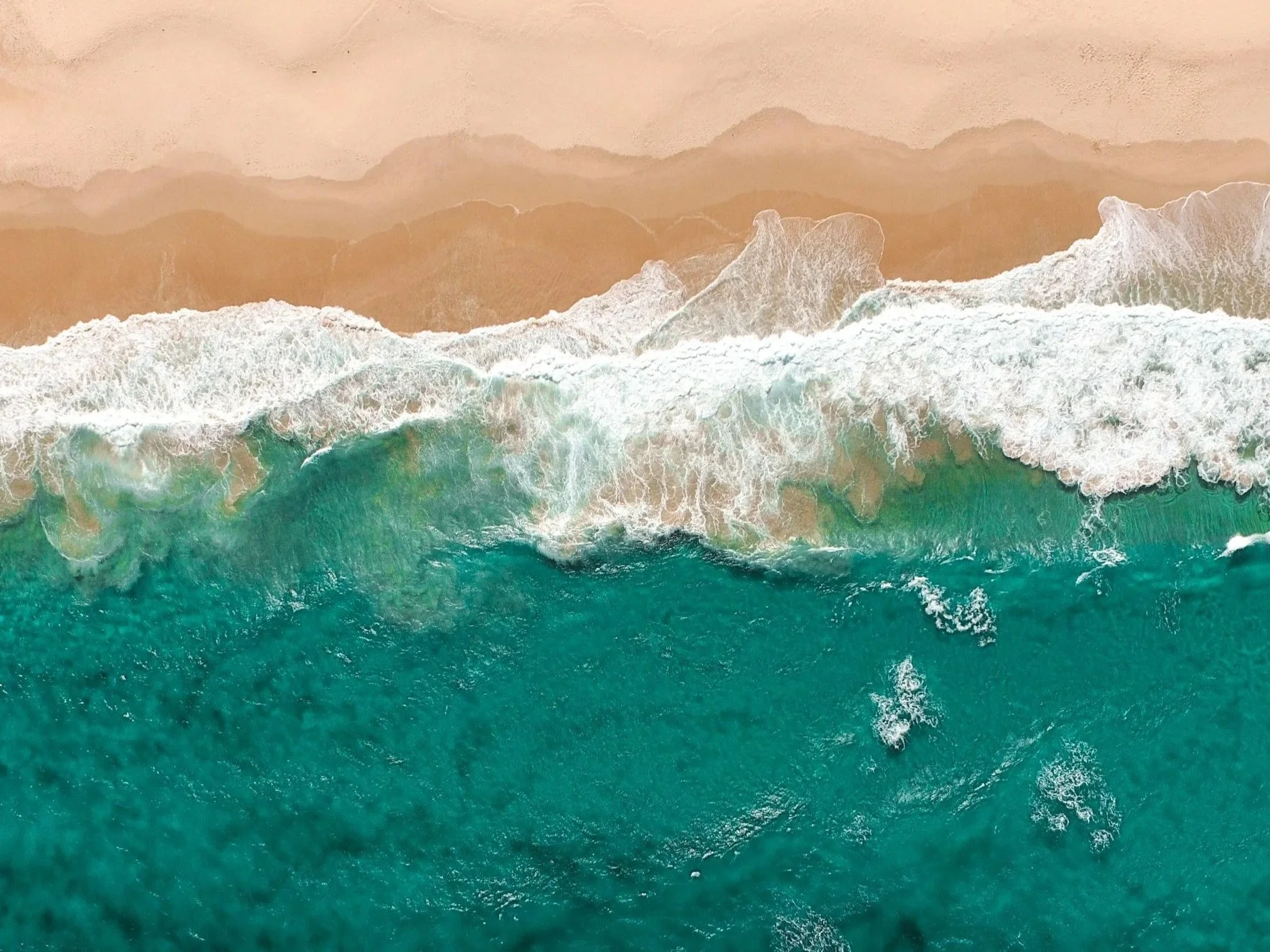 Birds-eye view of turquoise blue waves on a beach