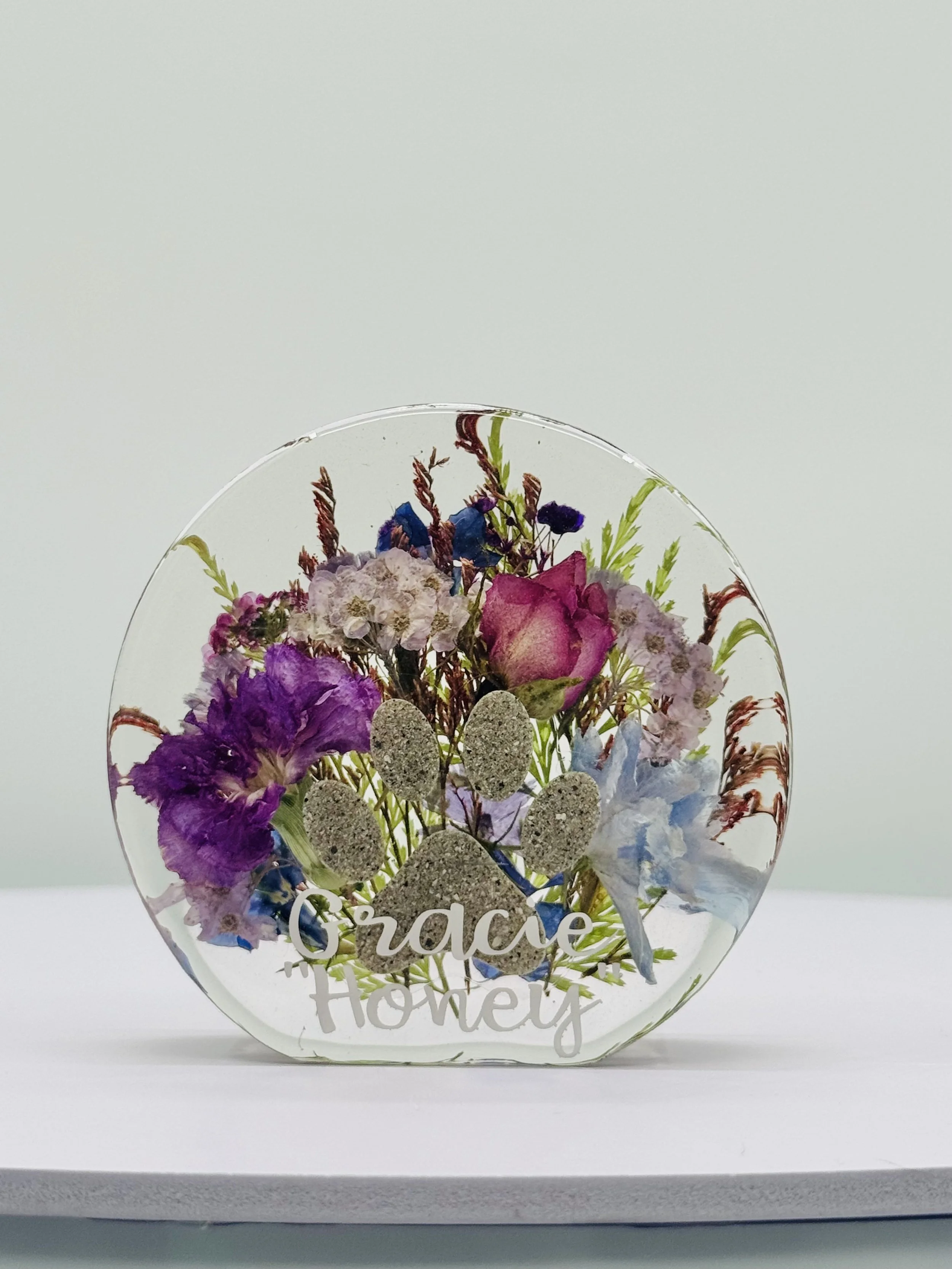 round resin pet memorial with paw print and flowers