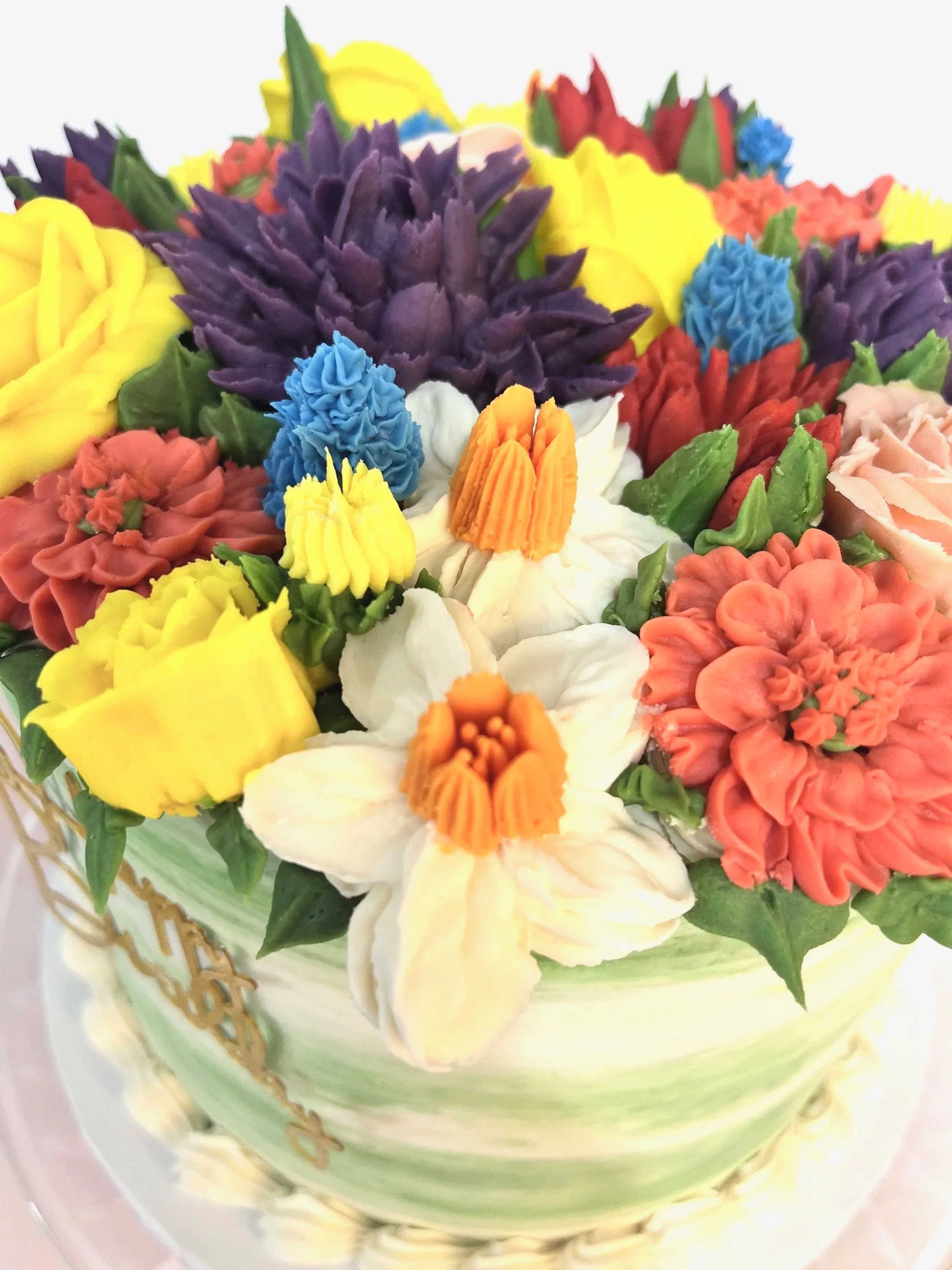 Colorfully decorated cake with various flower-shaped icing decorations in yellow, white, purple, red, orange, blue, and pink.