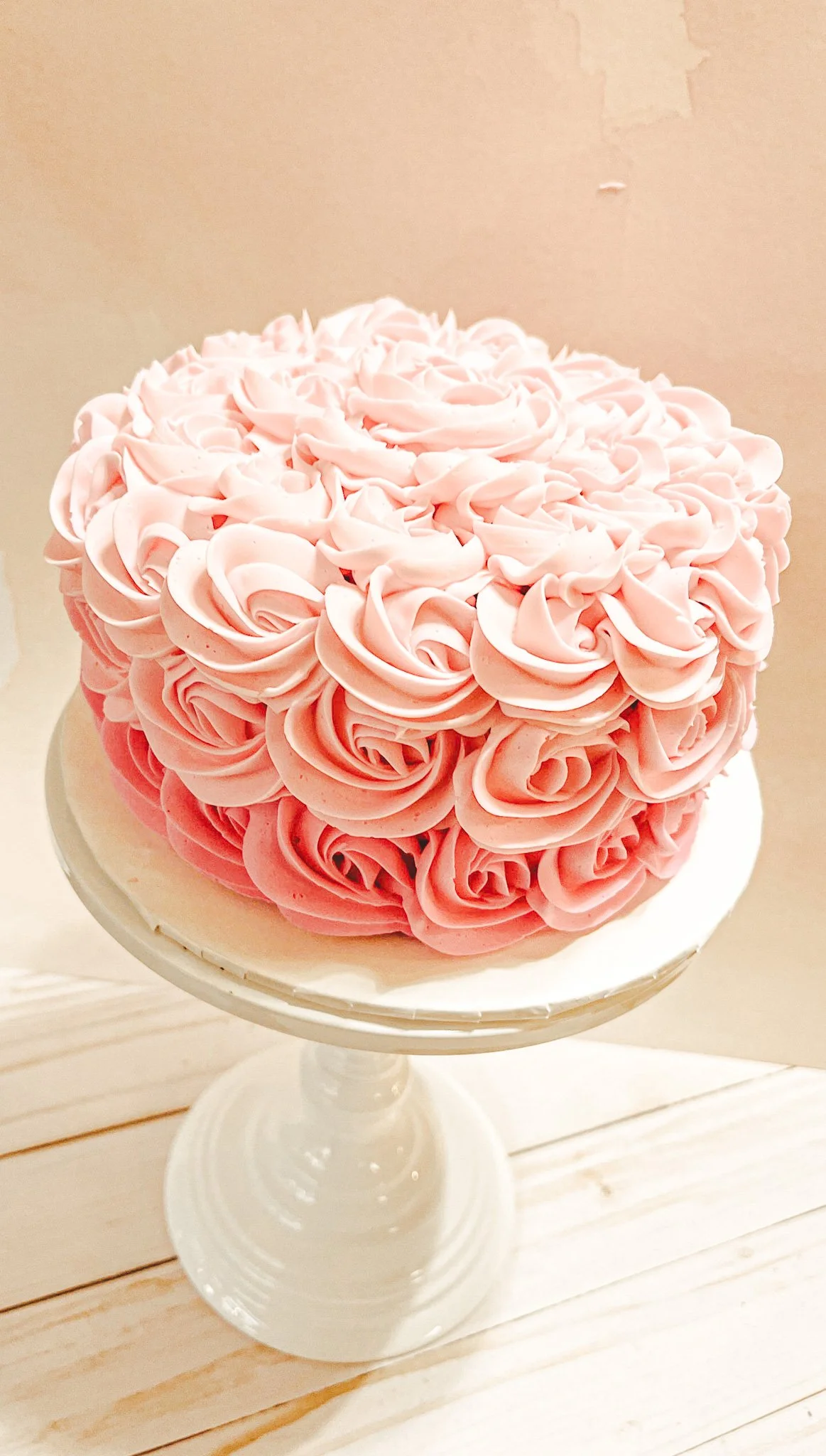 Pink rosette-patterned cake on a white stand