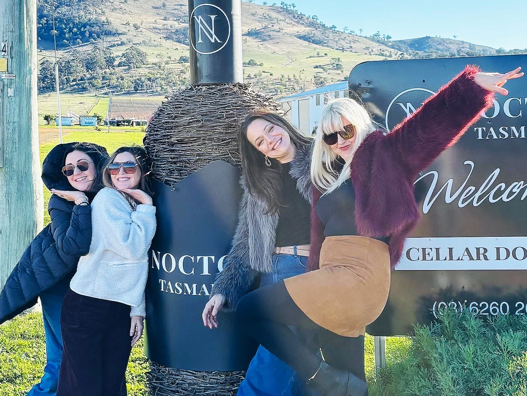 4 girls loving the vinyeard.  smiling and laughing as they pose for a picture.