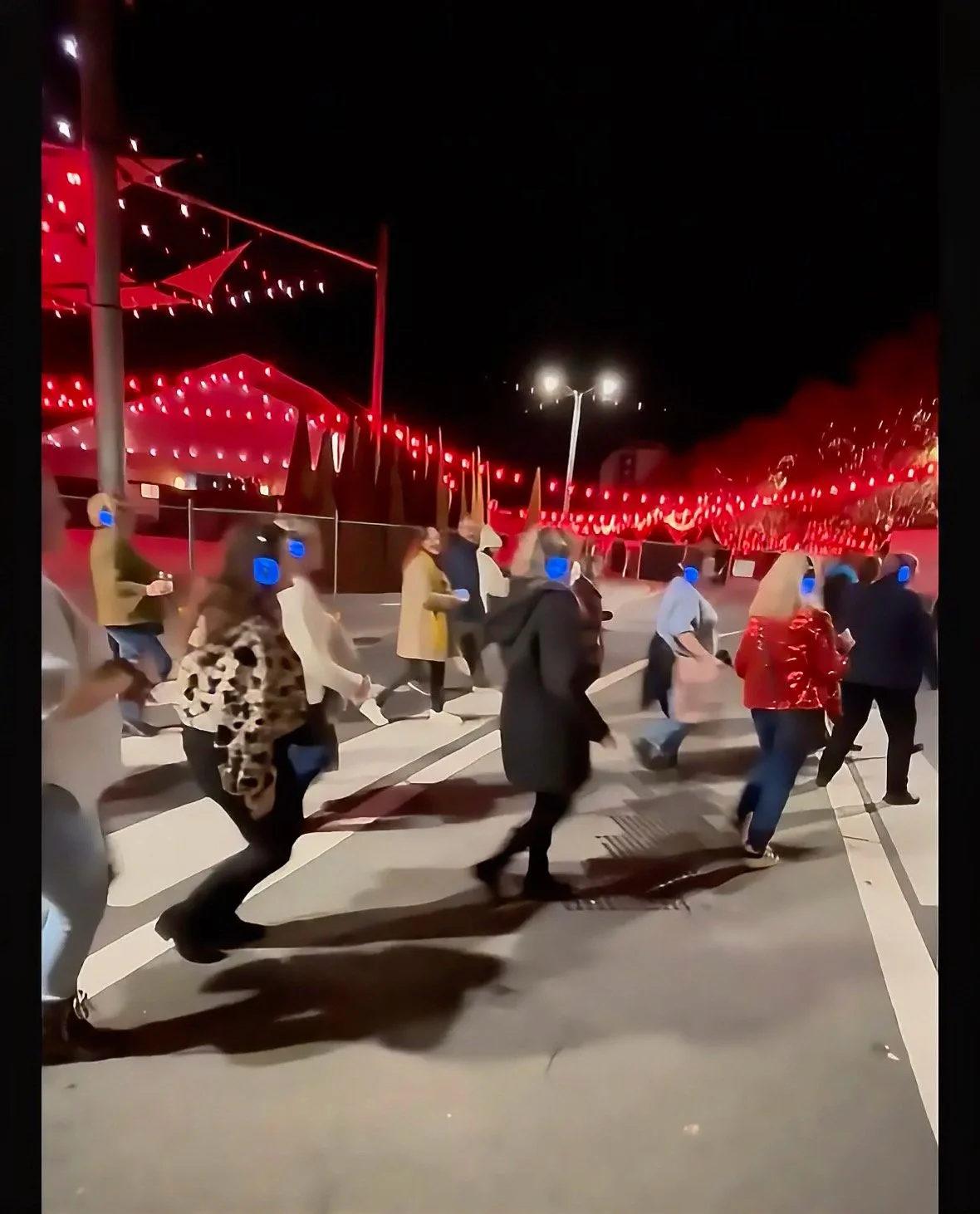 A group of people crossing the road at a zebra crossing, wearing Silent Disco headphones. Picture is at night.