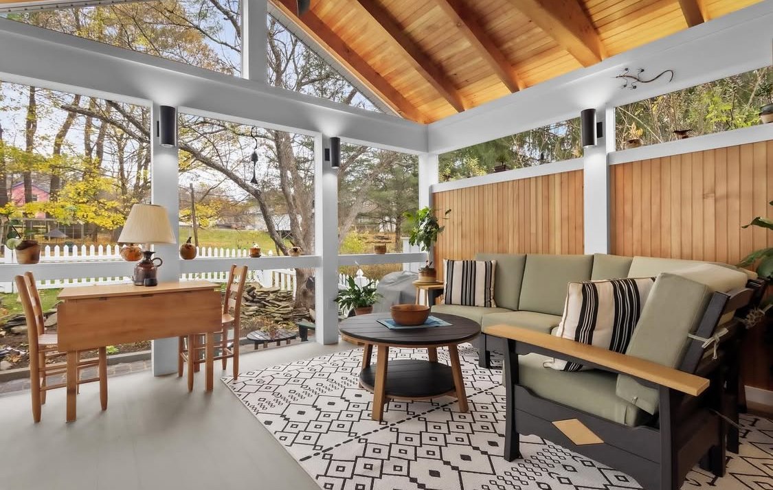 Custom porch/sunroom with large windows, wooden ceiling, and modern furniture.