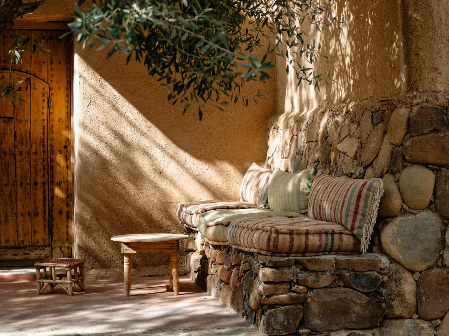 Garden courtyard at Berber Lodge near Marrakech, quiet seating area under an olive tree