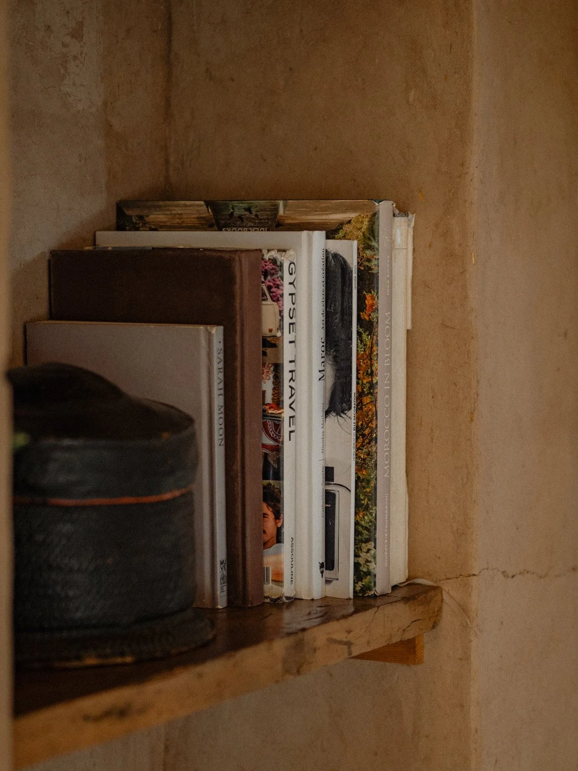 Built-in lime plaster bookshelf in a small Moroccan hotel, holding an arrangement of books and objects integrated into the architecture.