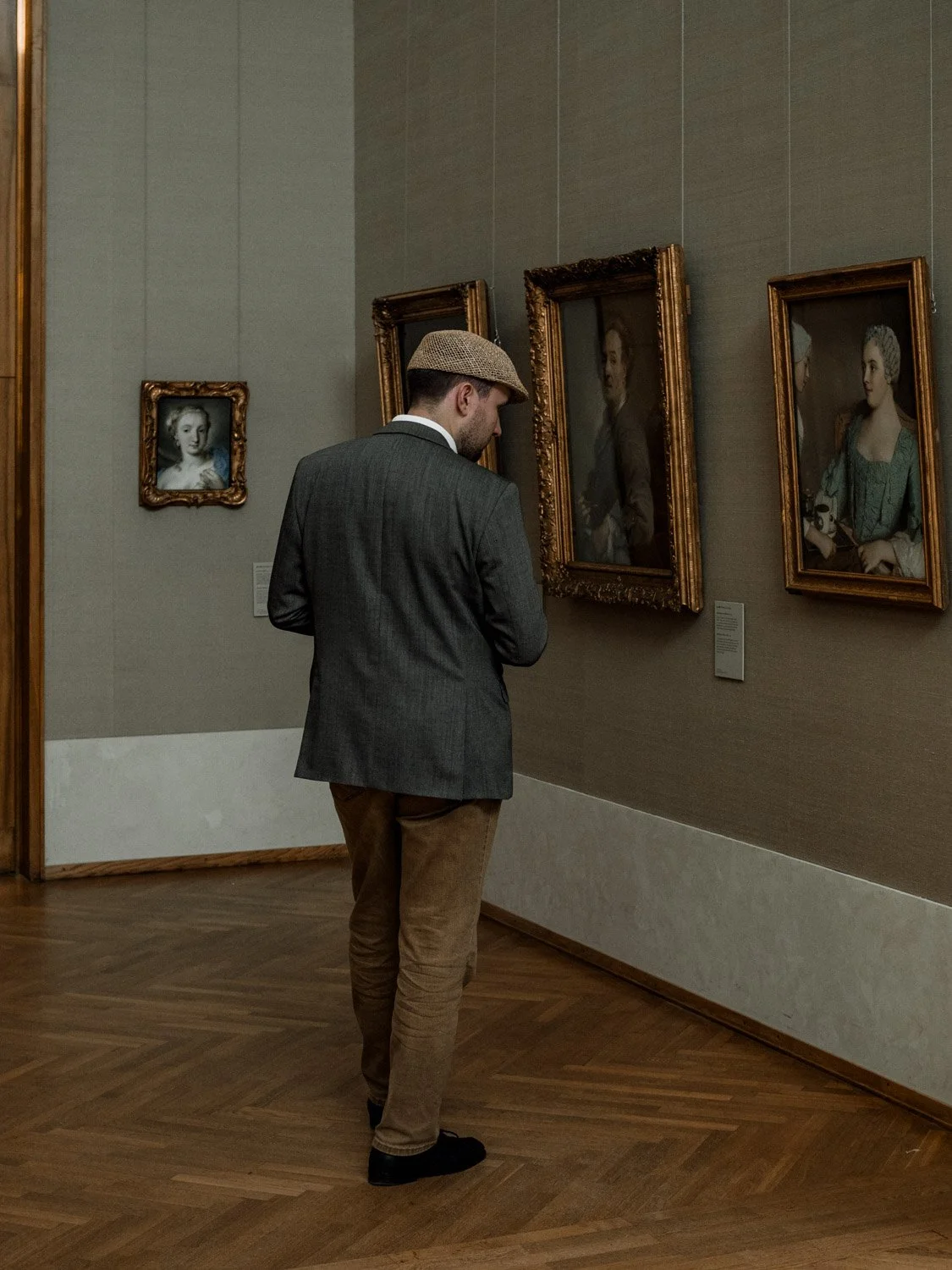 Man standing in a gallery room of the Alte Pinakothek surrounded by paintings, Munich, Germany