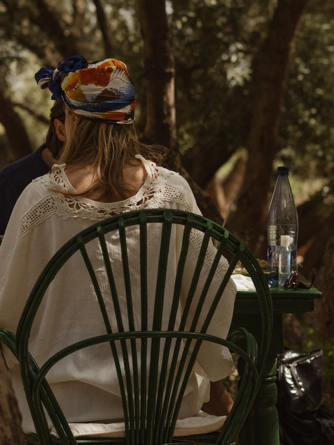 Outdoor lunch at Berber Lodge near Marrakech, guest enjoying a shaded garden meal with stylish outfit and colorful hair wrap