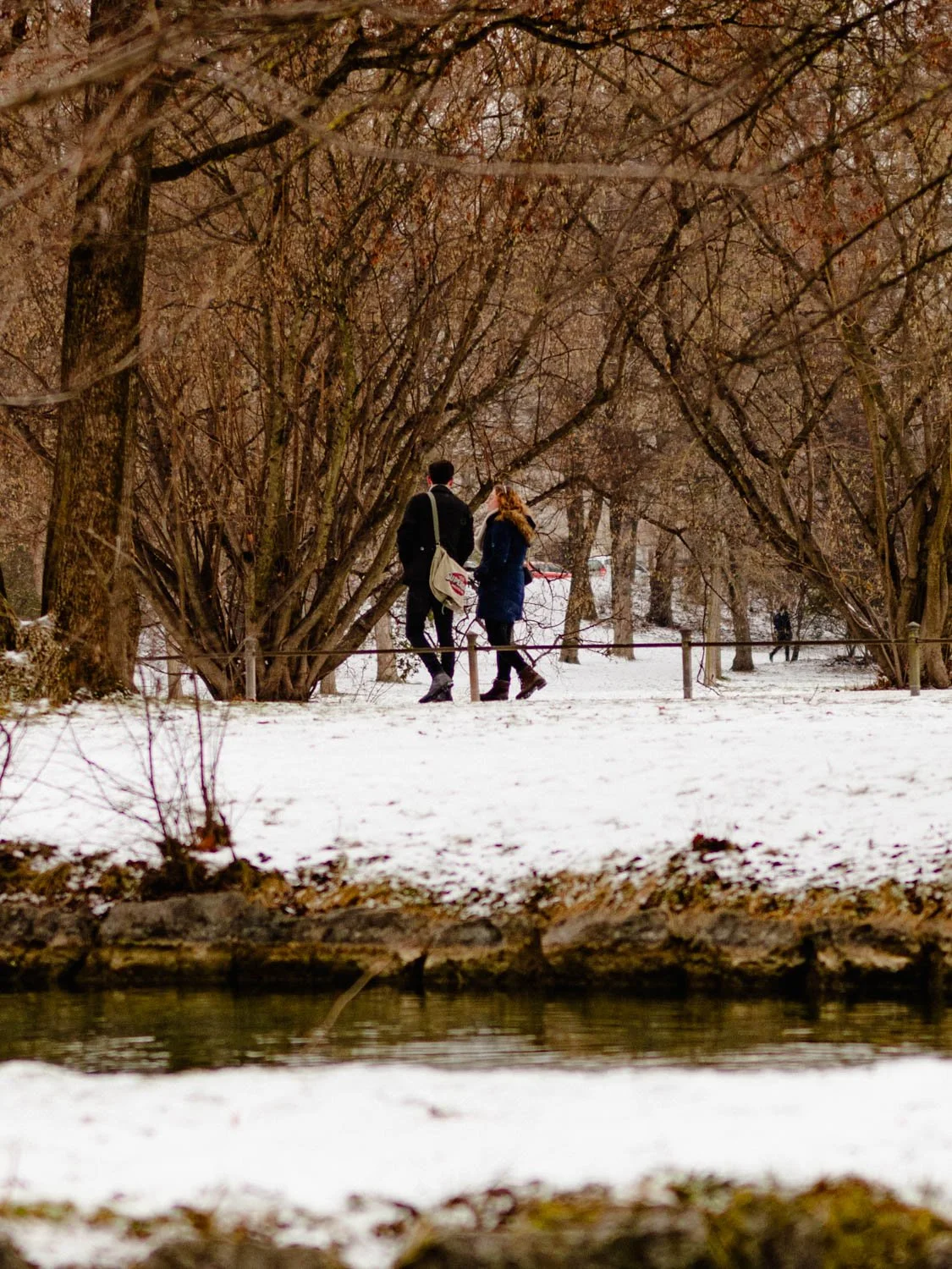 A couple walking on a snowy winter day in the Englischer Garten, Munich, Germany