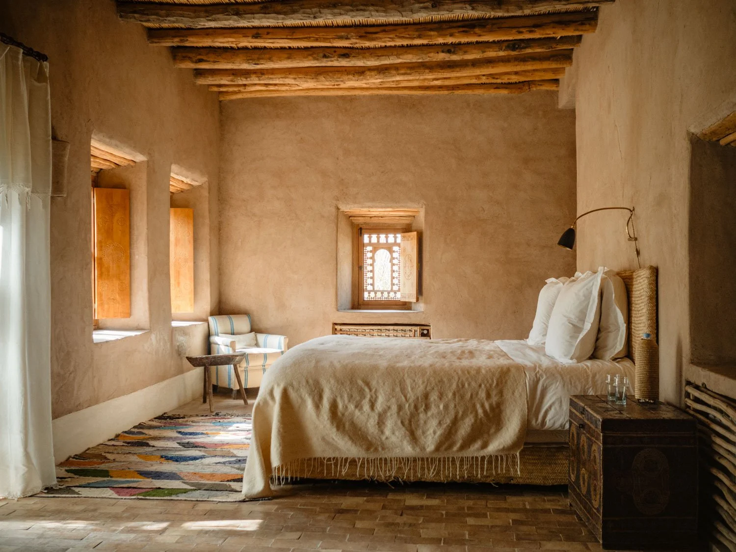 Suite interior at Berber Lodge near Marrakech, bed with earthen walls and natural light from the balcony
