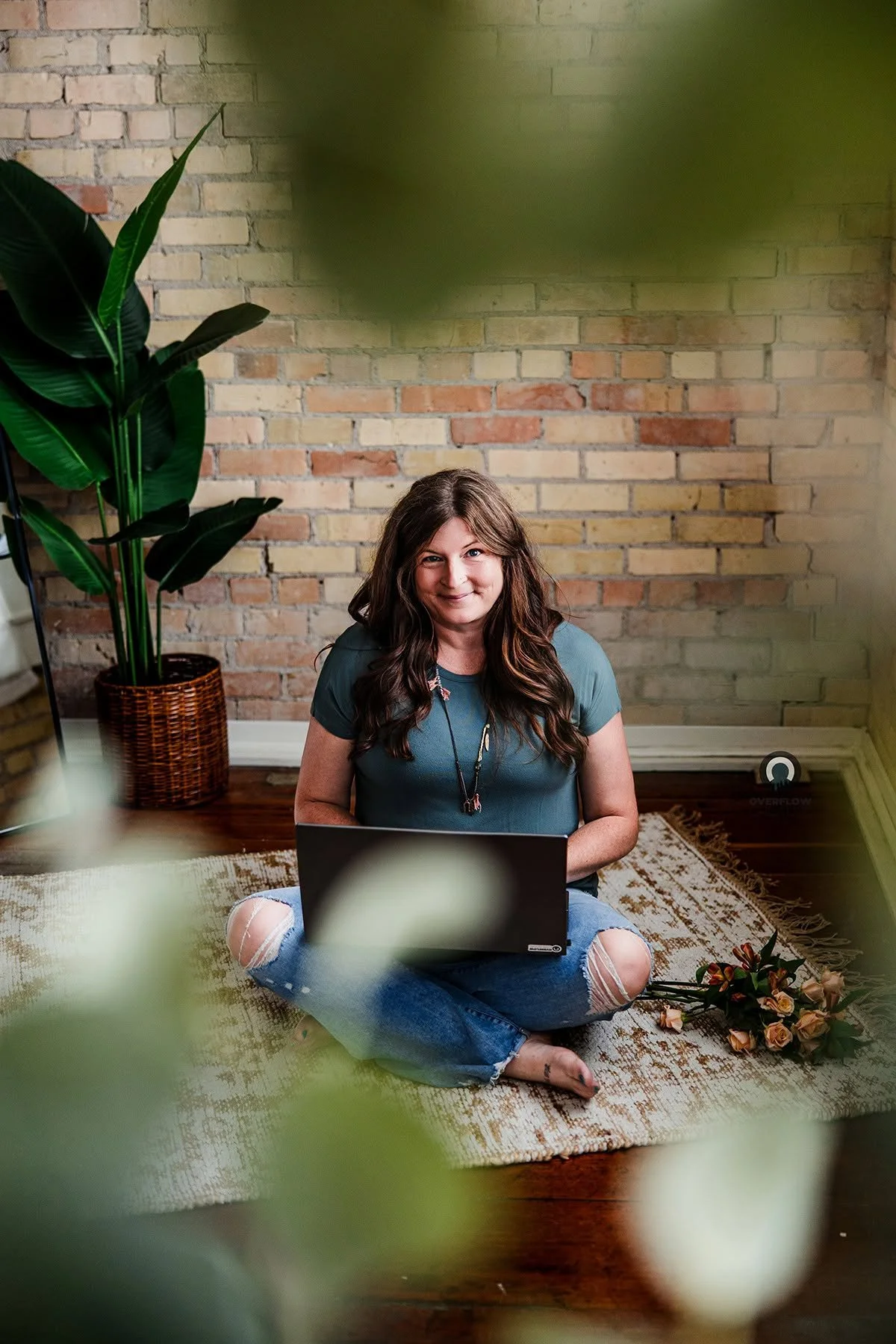 Bobbi Jo Hamilton sitting with her laptop in a warm, nature-inspired space.
