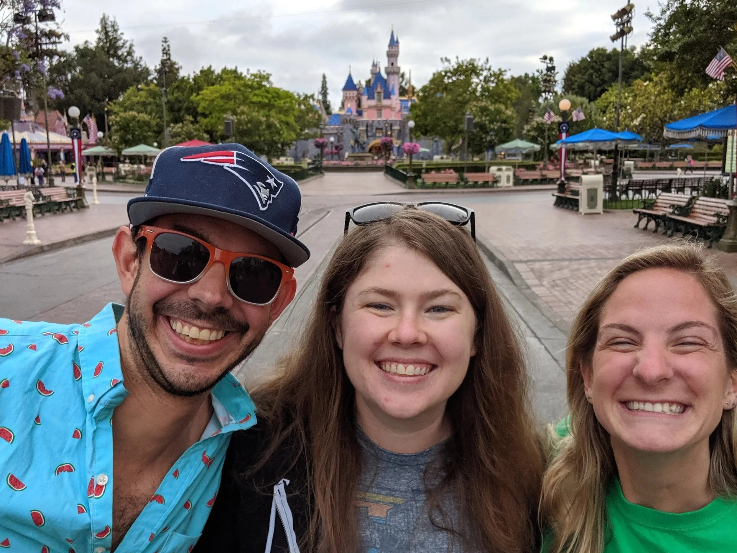 Three smiling people taking a selfie at Disneyland with a castle in the background.