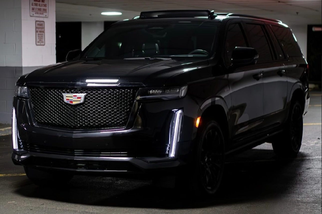 Black Cadillac SUV parked in a dimly lit parking garage with illuminated vertical daytime running lights.
