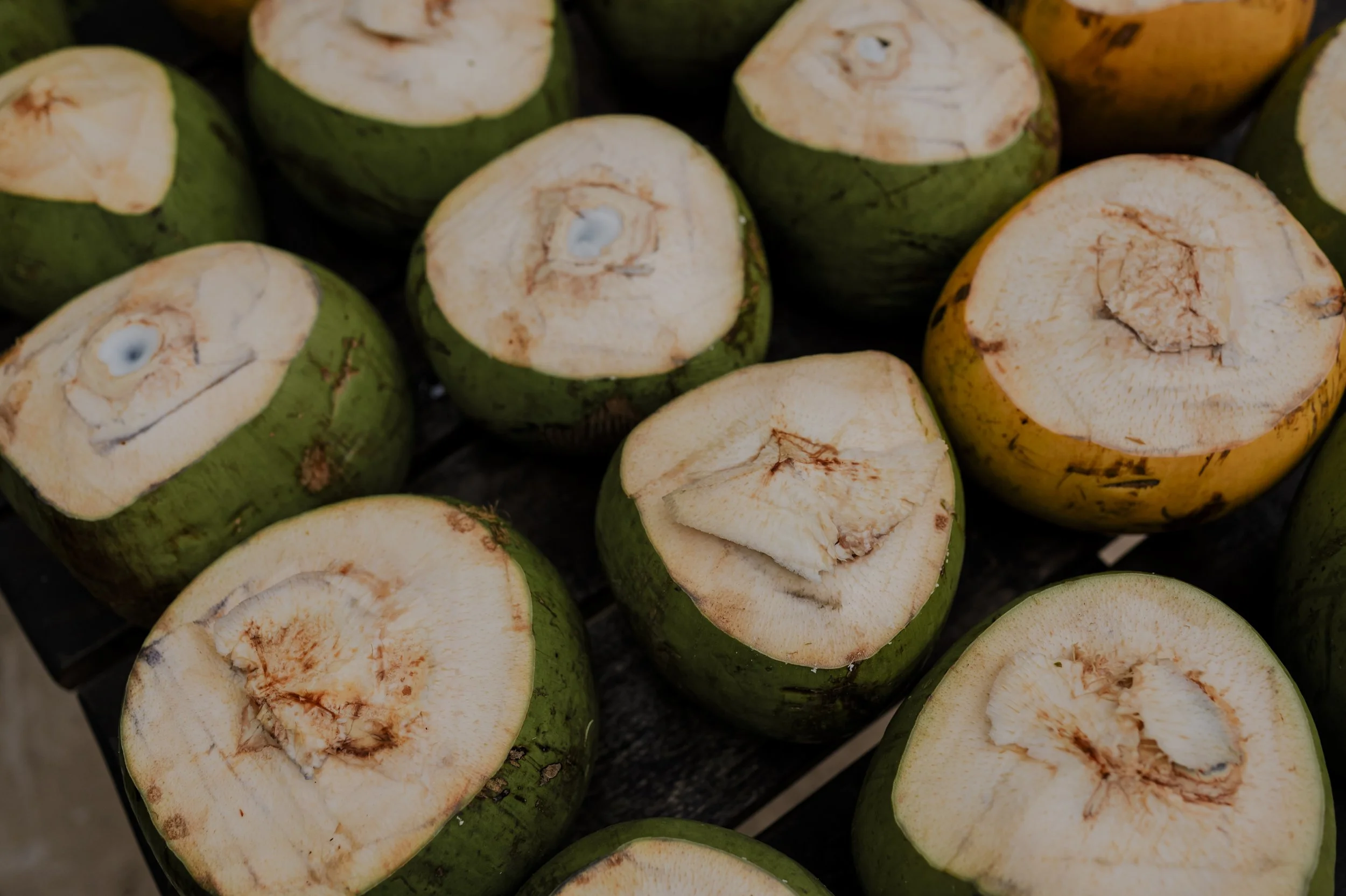Cross-sectioned green and yellow coconuts arranged on a surface.