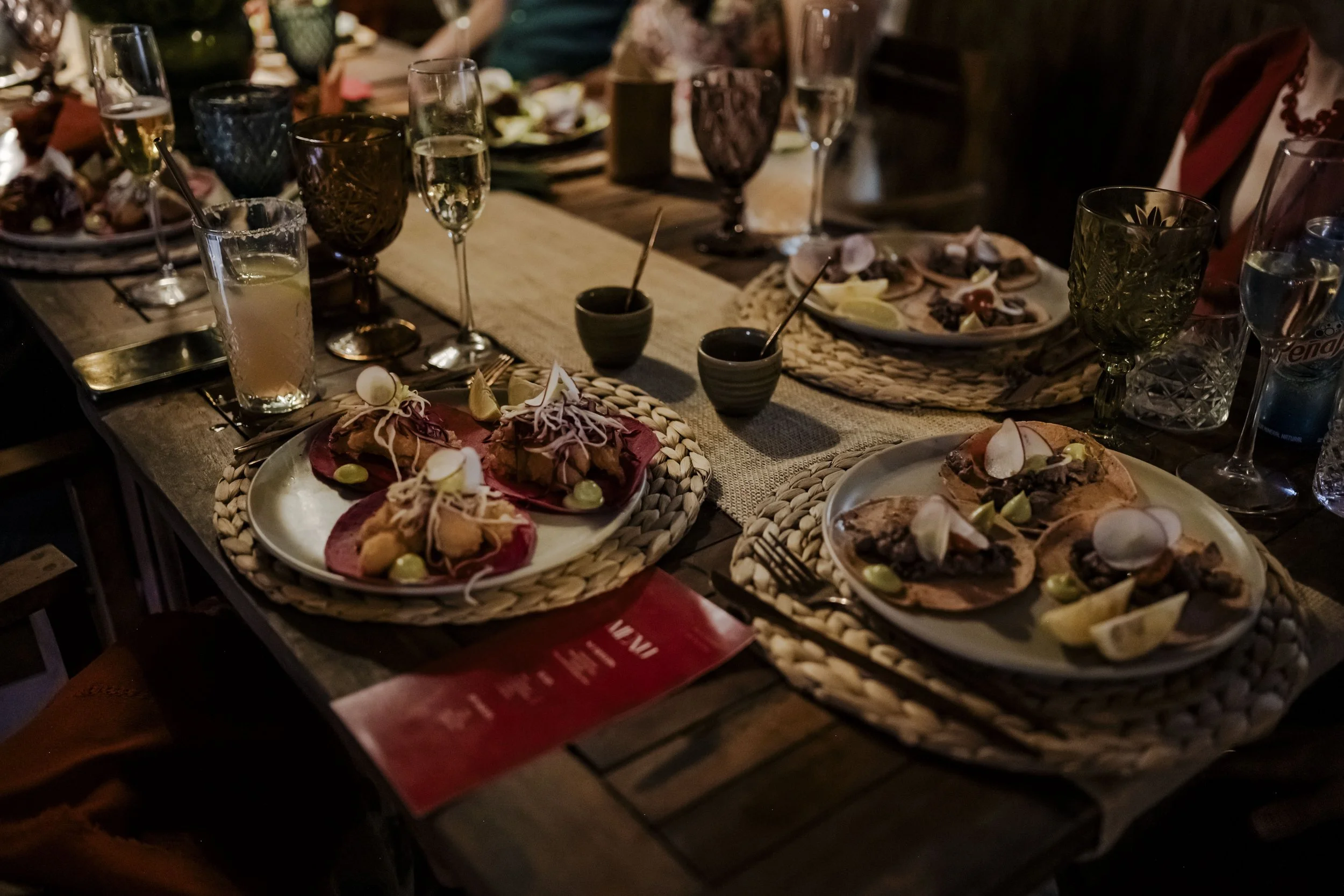 A dinner table with plates of tapas, small bowls, wine glasses, and drinks.