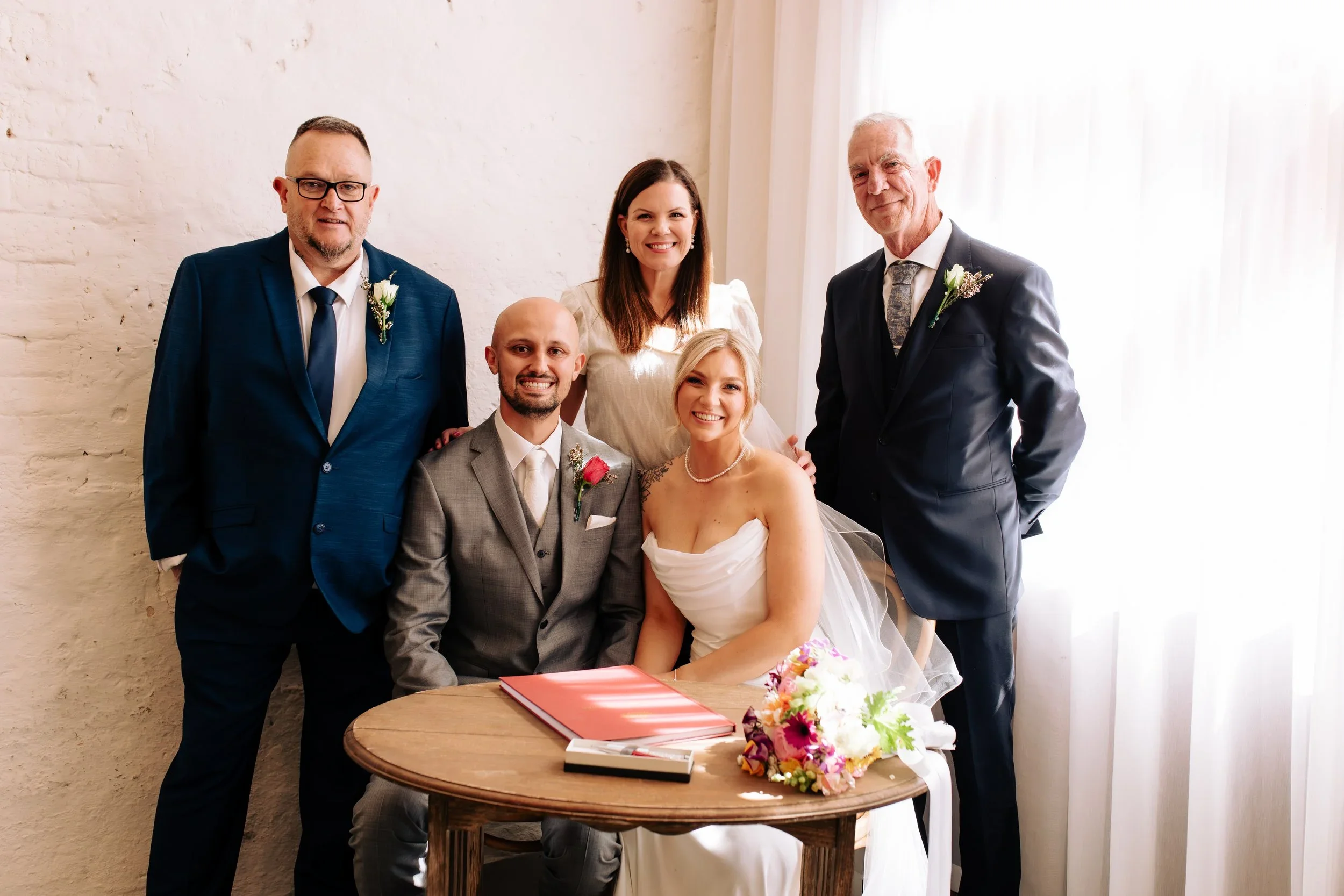A couple signing the marriage register with both fathers and Niamh standing behind them