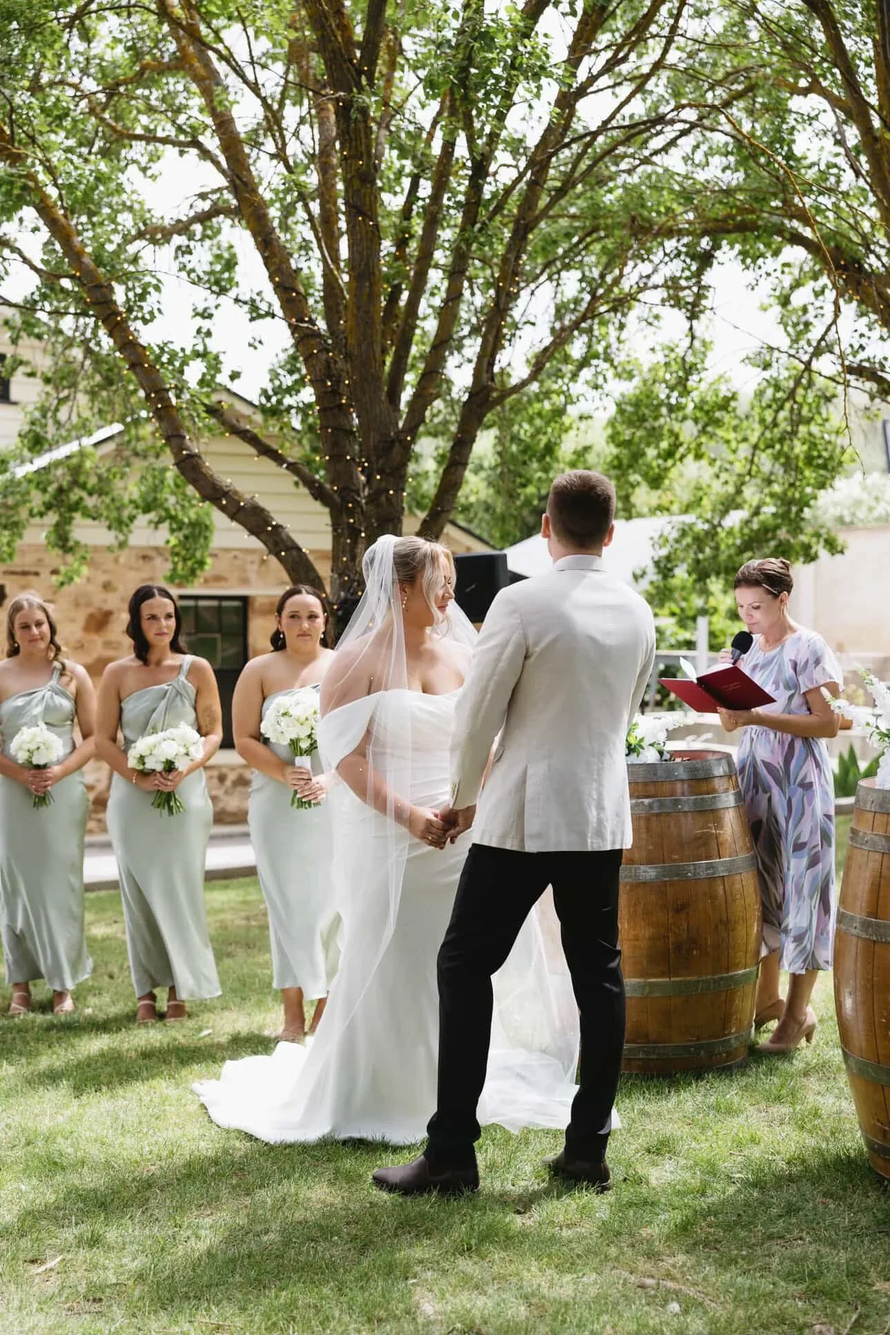 Niamh reading from her red Avoca Weddings folder at an outdoor garden wedding with bridesmaids in sage dresses