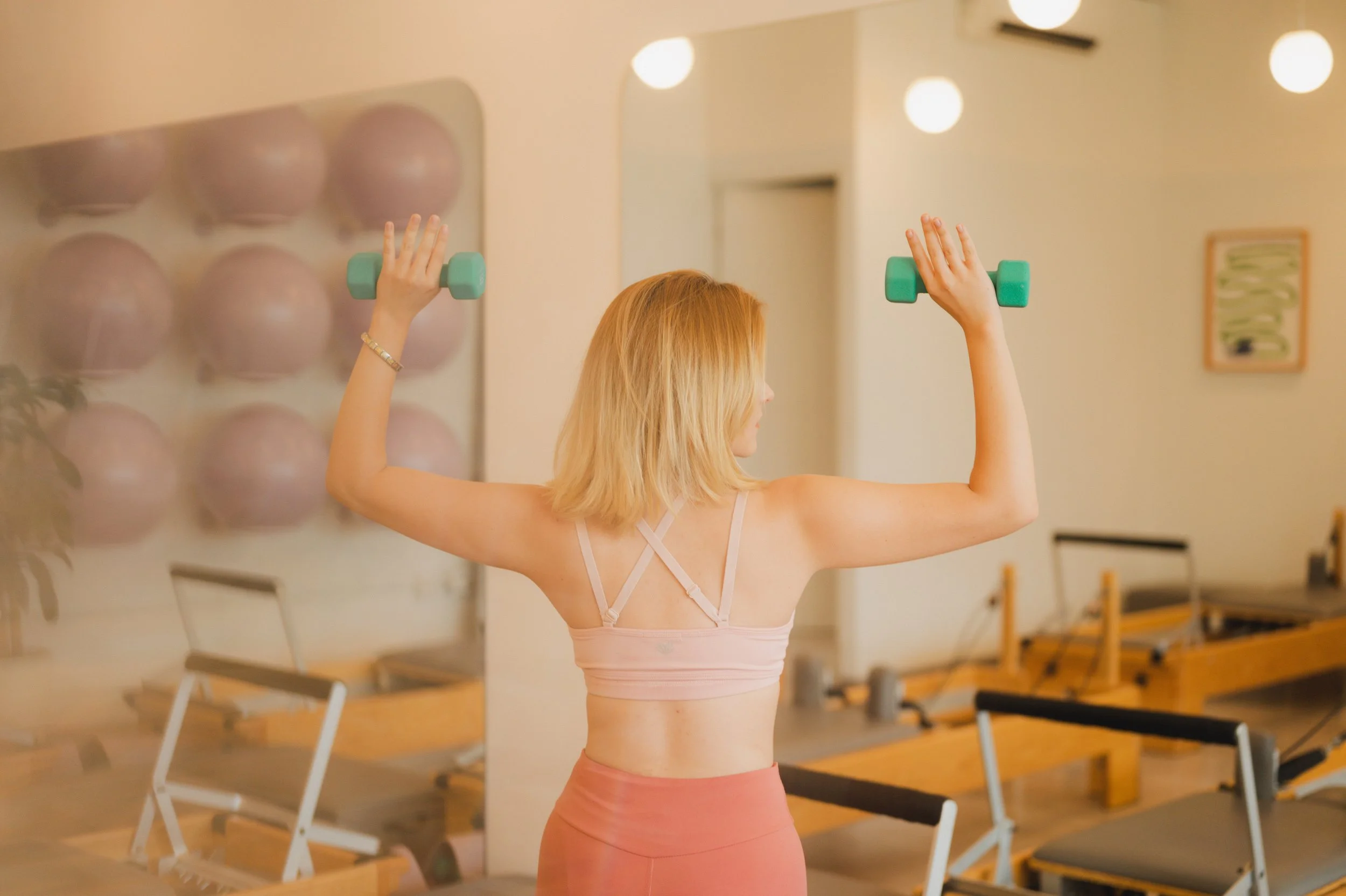 Mujer haciendo ejercicio de brazos con mancuernas en un gimnasio