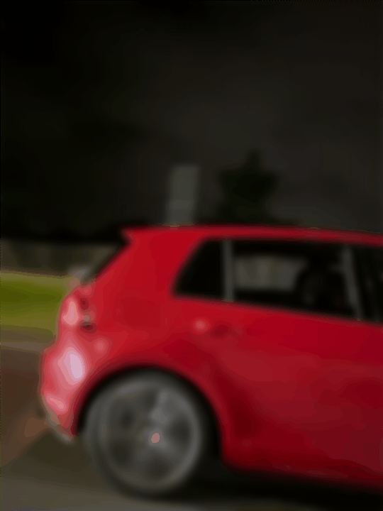 Blurred red car driving at night on the street with a dark sky and street lights.