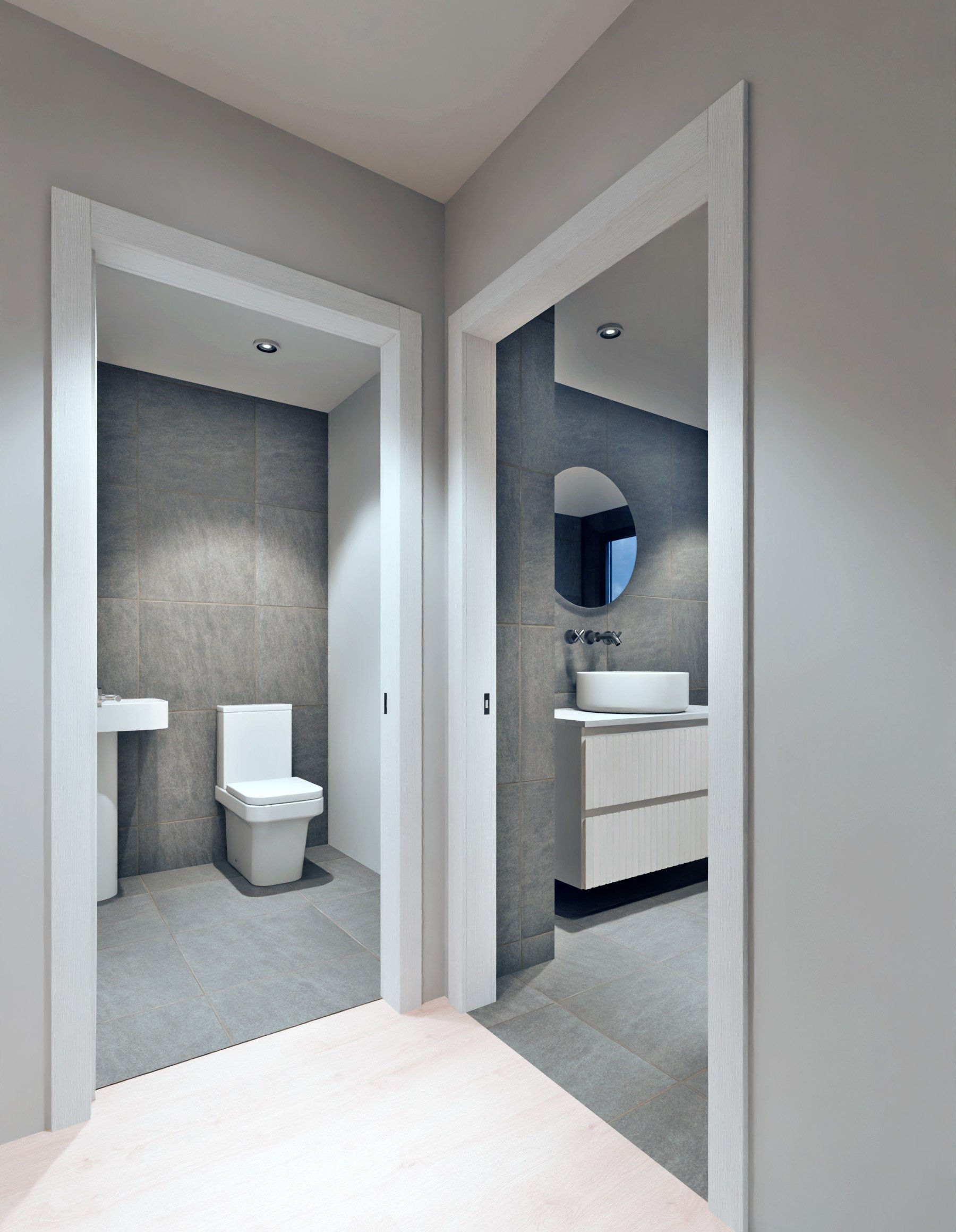 Modern bathroom with two separate toilet and sink areas, grey tiles, white fixtures, round mirror, recessed ceiling lights, and closed sliding doors.