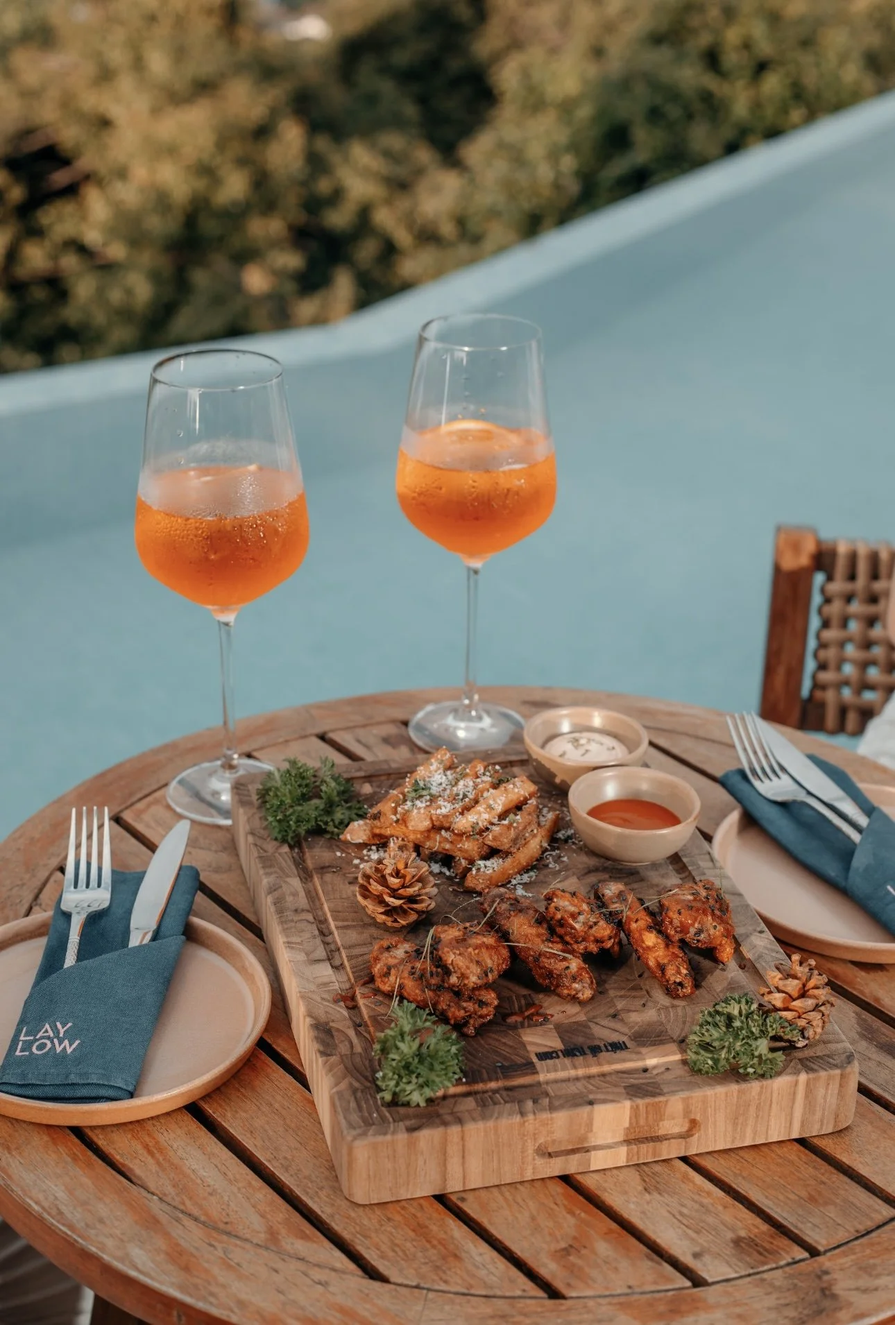 Flat lay of an outdoor table with cocktails, appetizers, and dipping sauces — colorful content for hospitality or food brand.