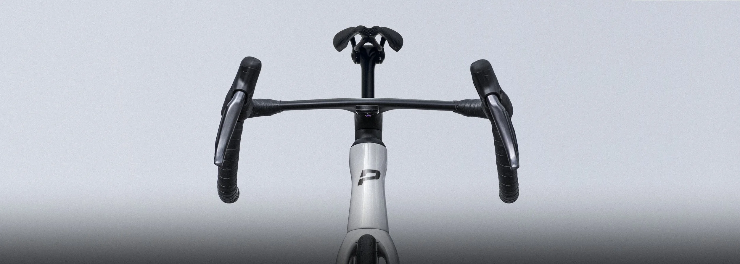 Front view of a white and black bicycle, showing the handlebars and seat against a plain gray background.