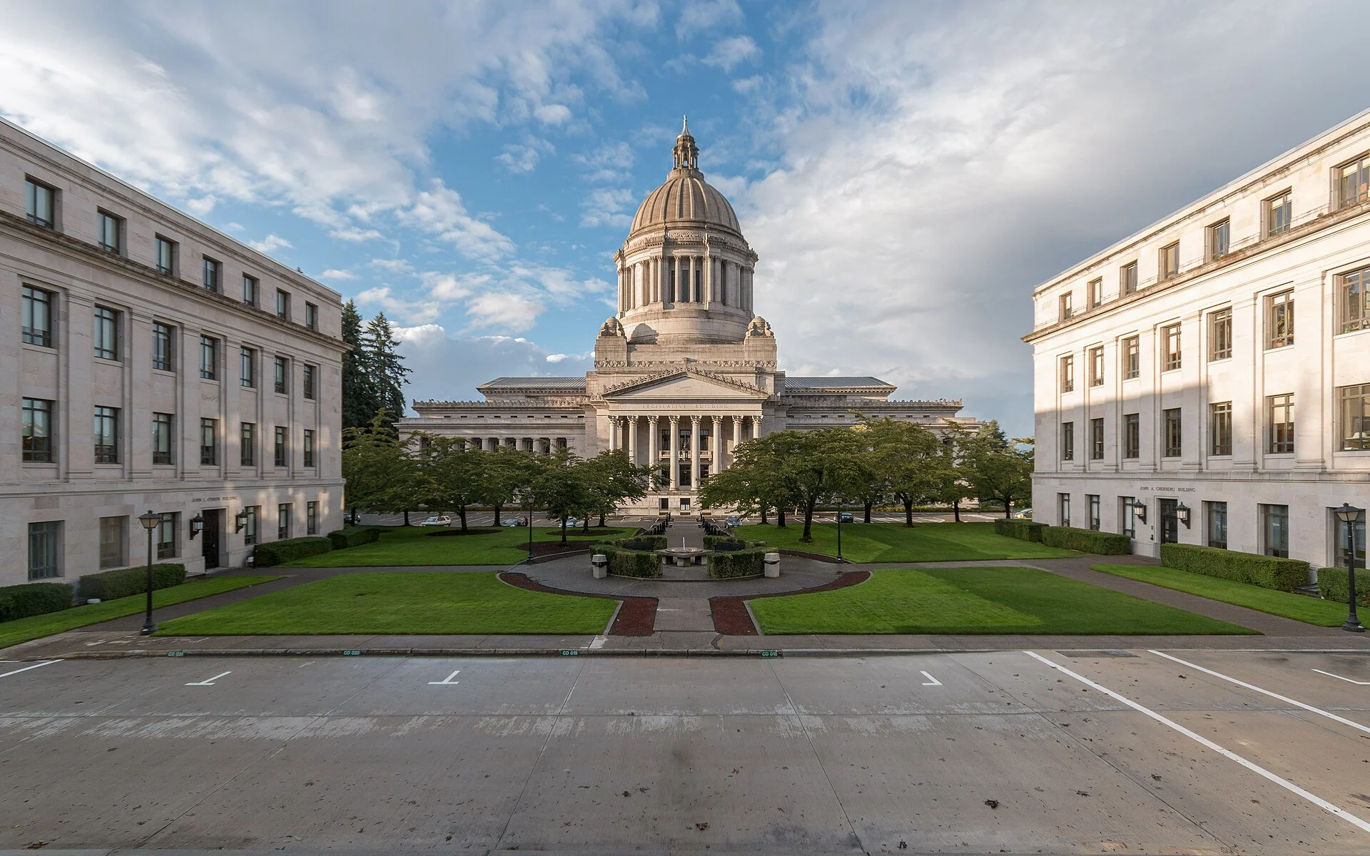 The Washington State Capitol in Olympia, a domed legislative building at the end of a long lawn between two office buildings.