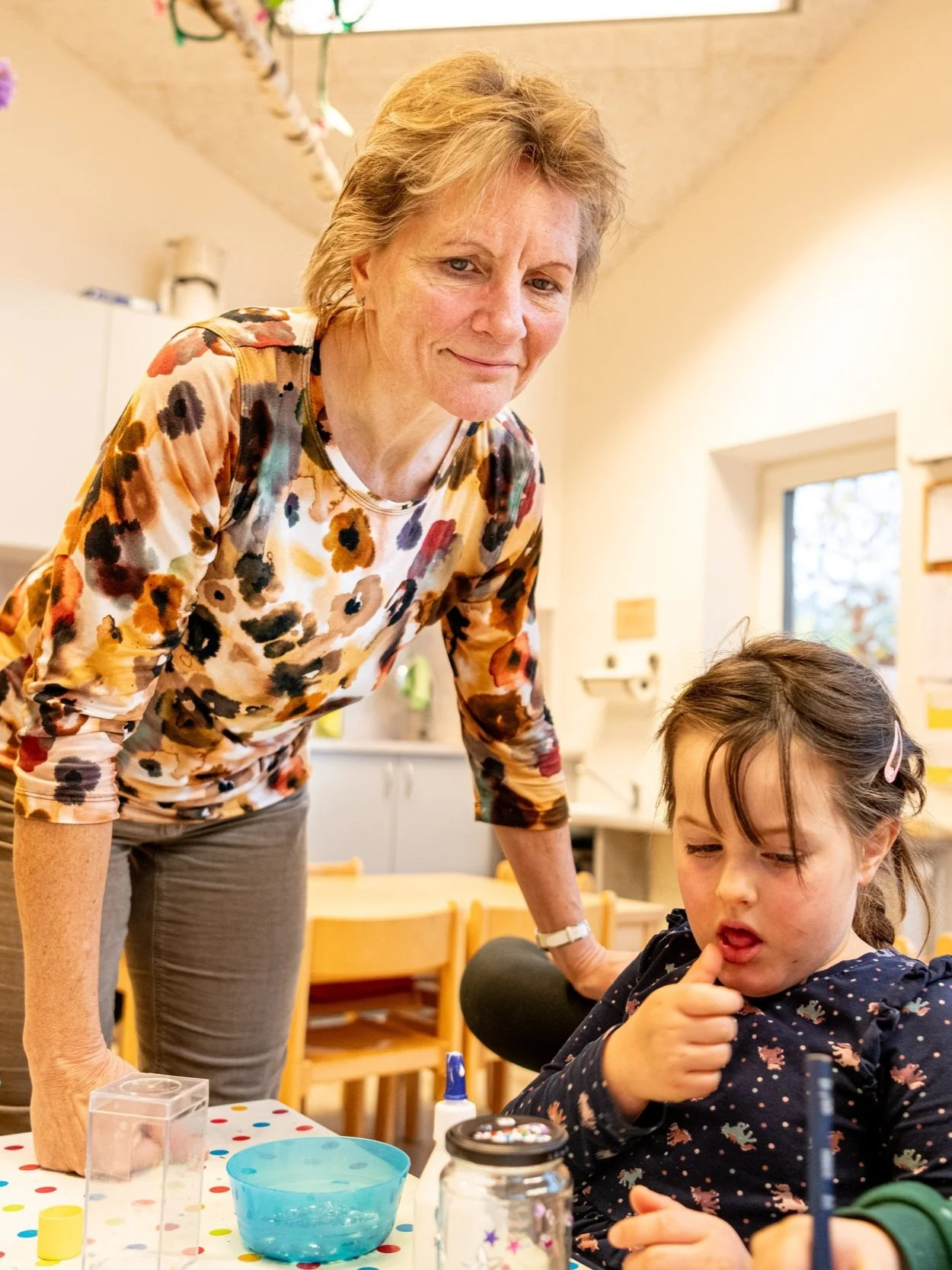 Leni Kiga - Kind bastelt mit Erzieherin