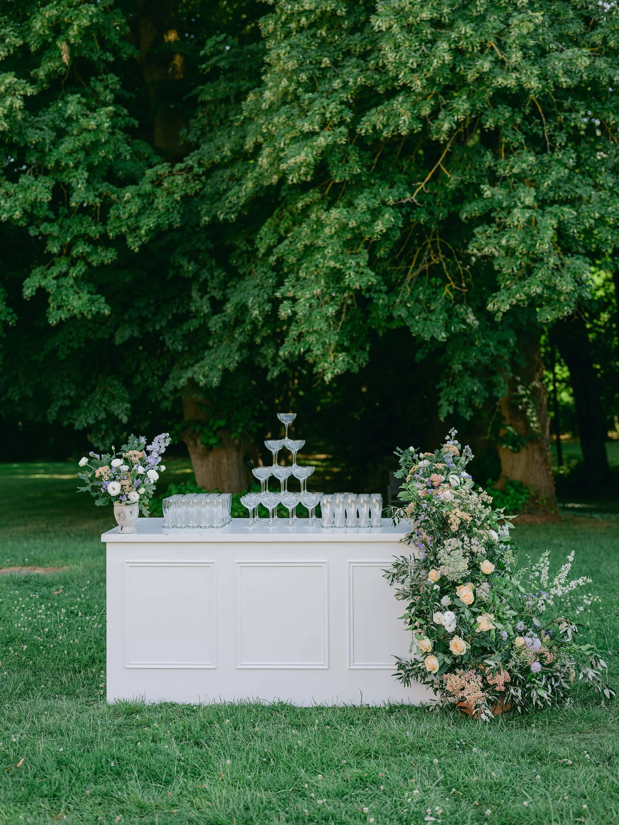 Outdoor wedding cocktail set beneath the trees at Château de Champlâtreux