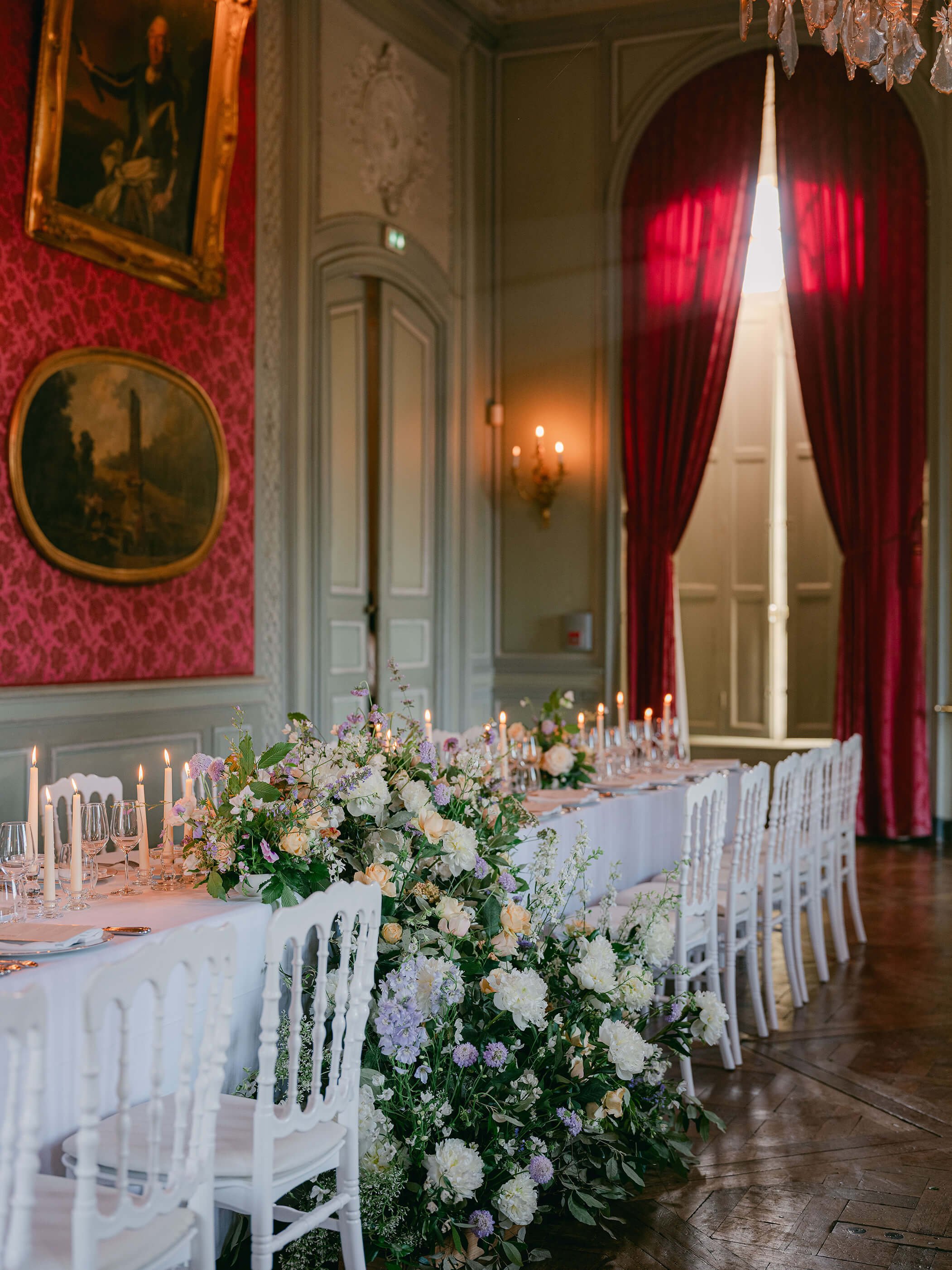 Wedding dinner tables decorated with seasonal flowers inside Château de Champlâtreux