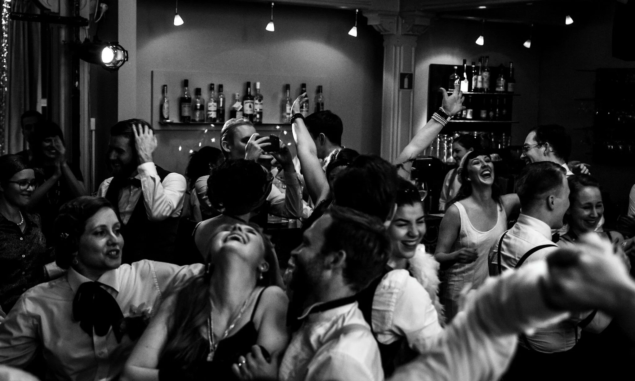 En gruppe mennesker ler og danser i en bar. Julefest på colonialen.