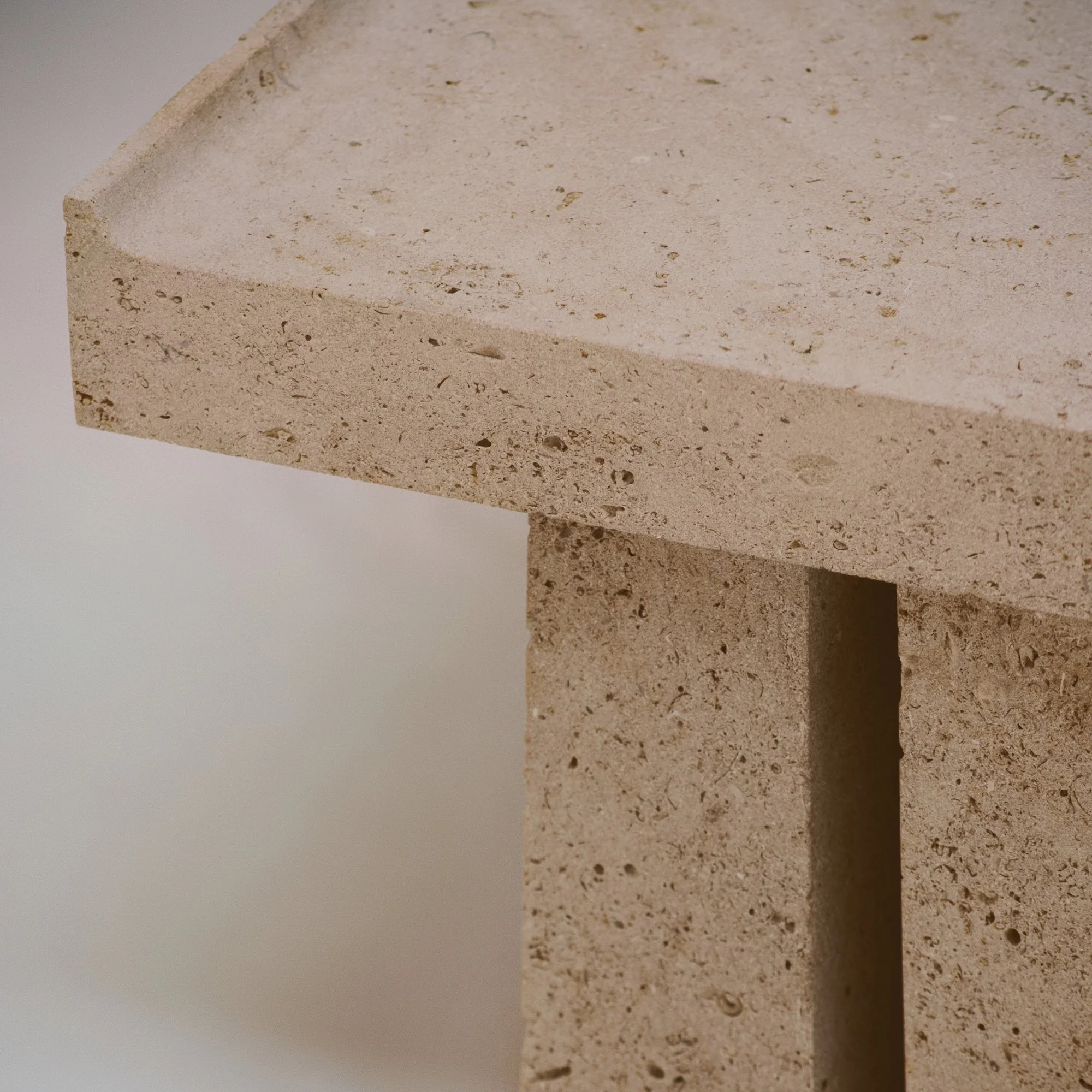 Zoom sur une surface en pierre de couleur beige avec une texture poreuse et un bord droit.