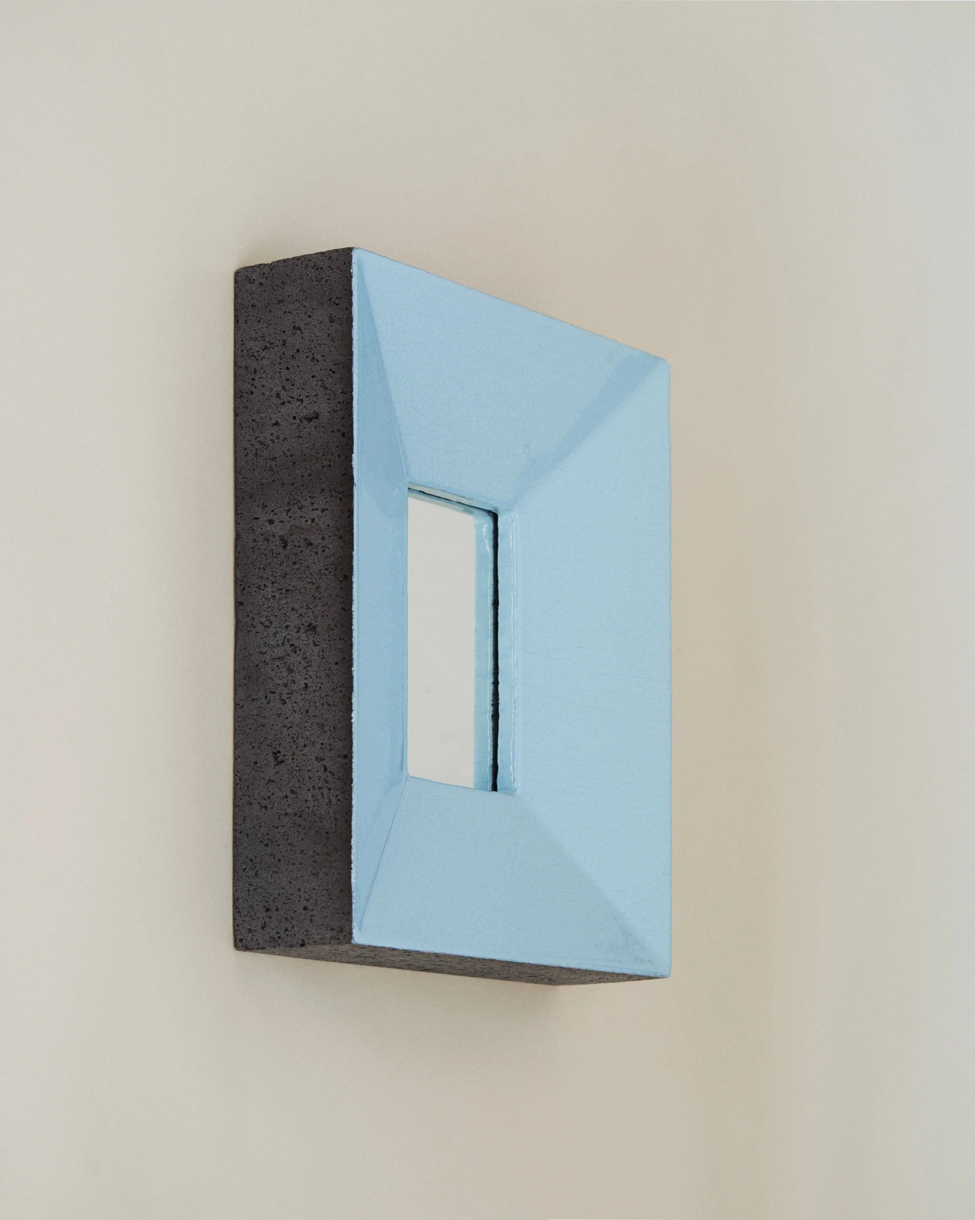 Miroir peint en bleu clair, montée sur un mur blanc.