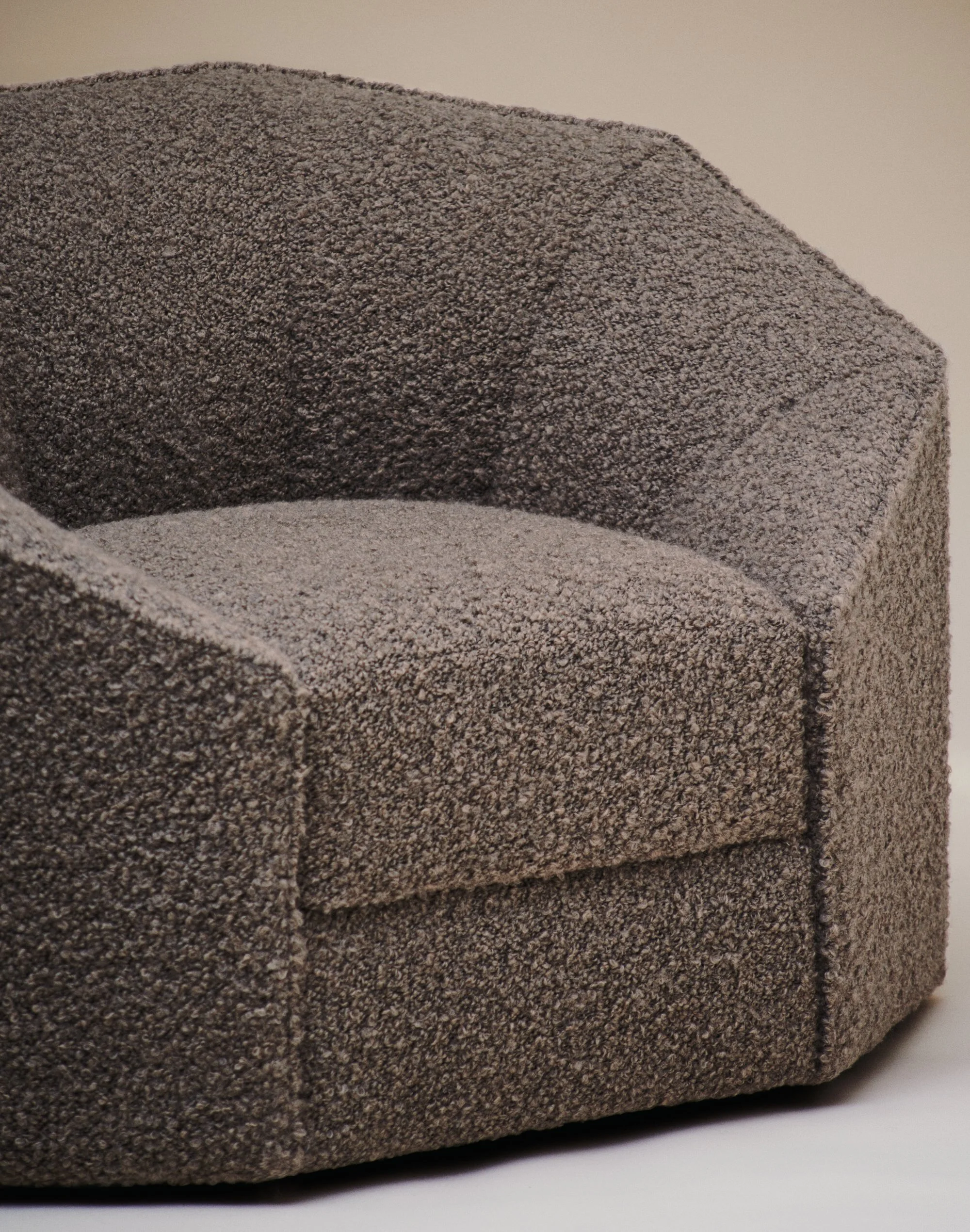 Fauteuil en tissu gris avec une assise arrondie et un dossier incurvé