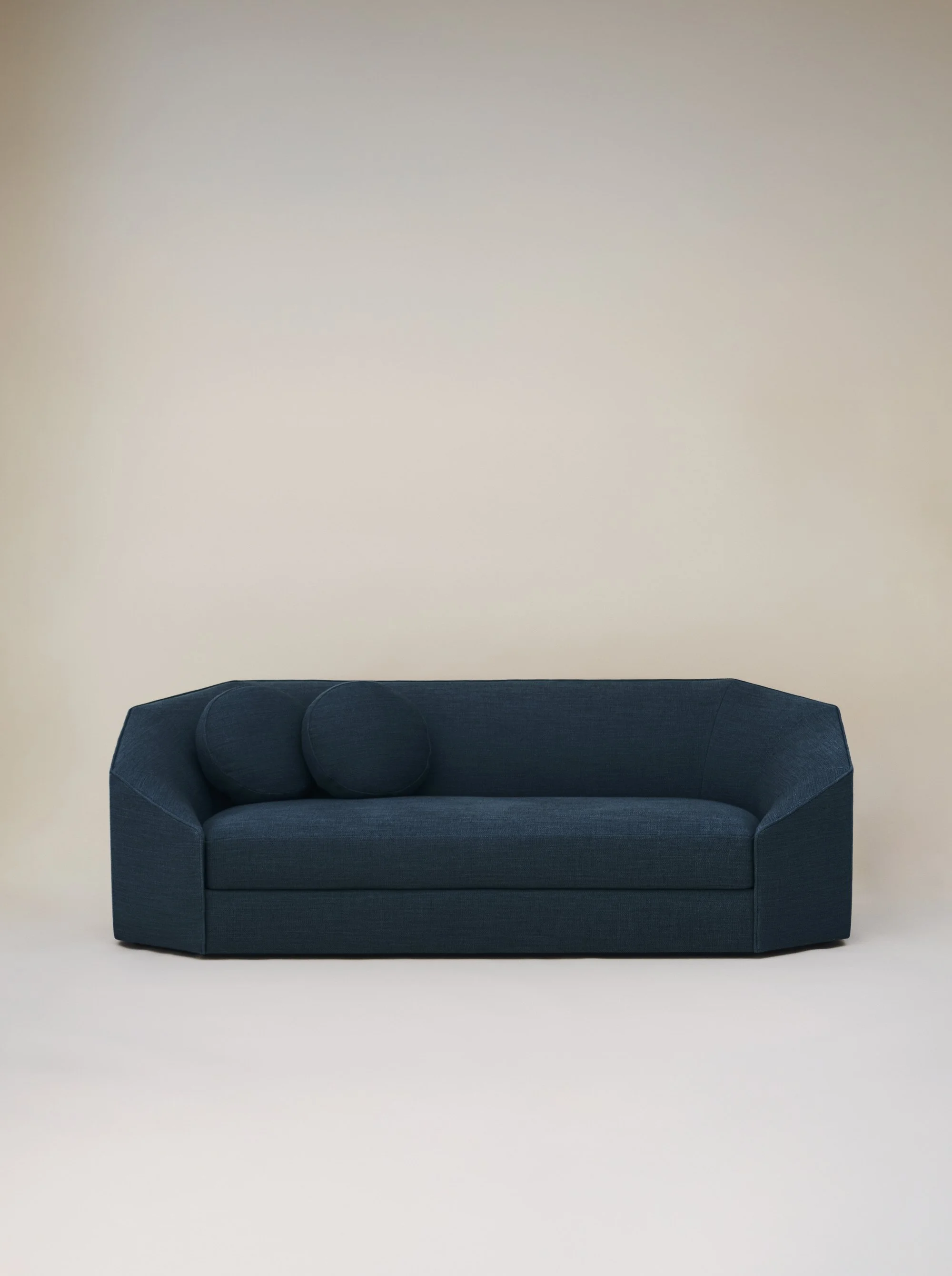 Canapé bleu foncé avec deux coussins ronds sur un fond beige simple