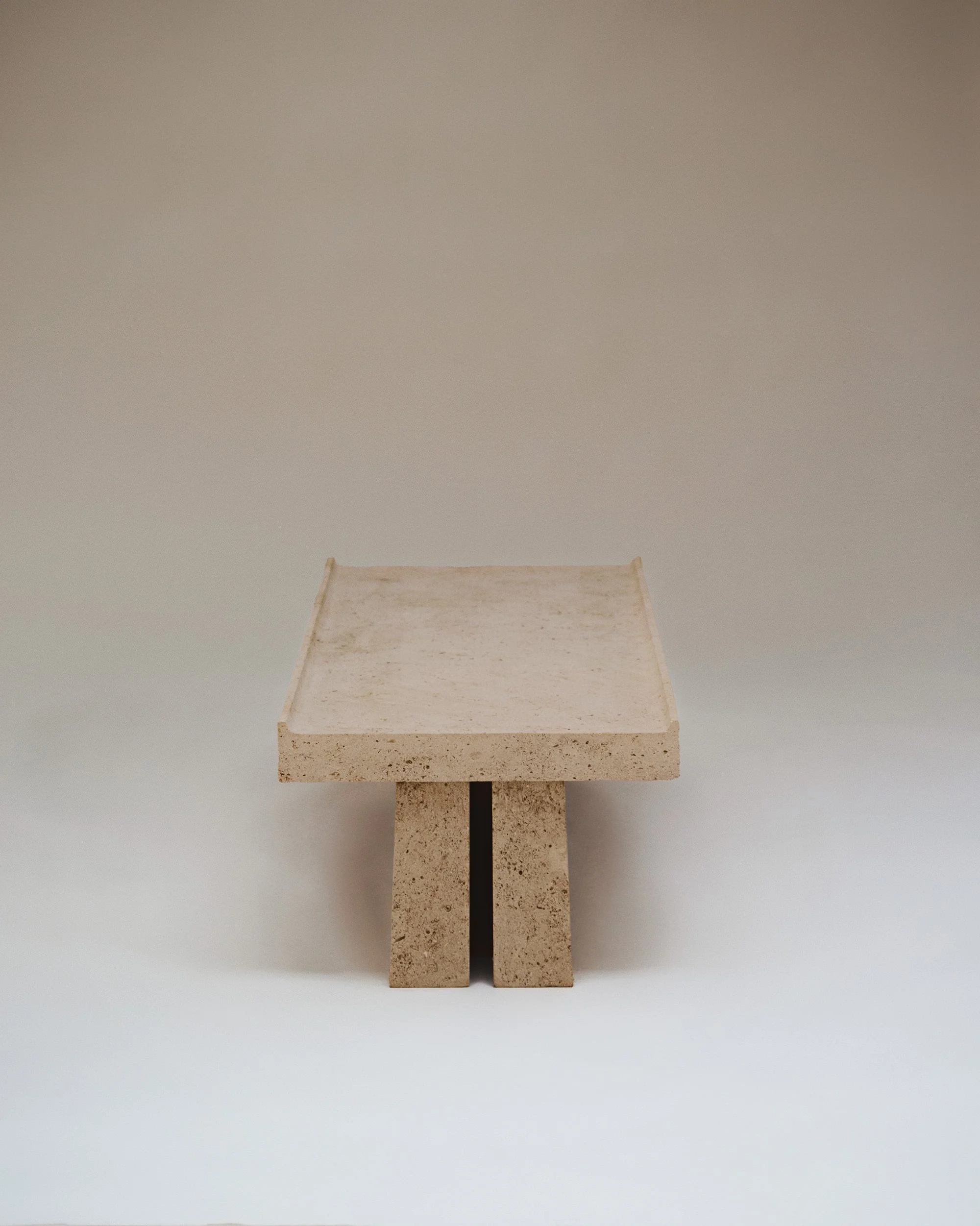 Une table basse en pierre ou en béton, placé contre un mur neutre.