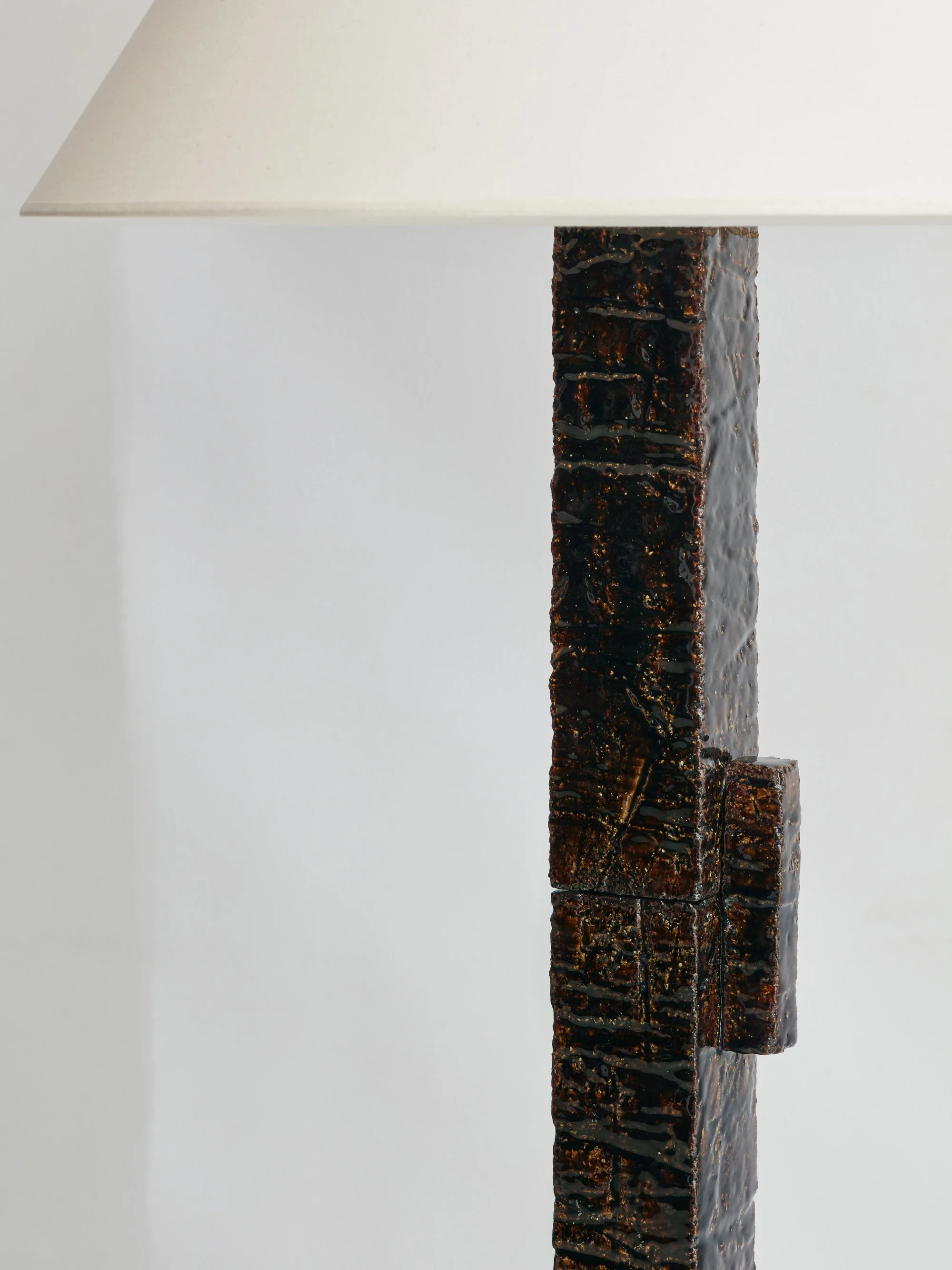 Lampe de table avec un pied en blocs de pierre recouverts de résine noirâtre, sur fond blanc