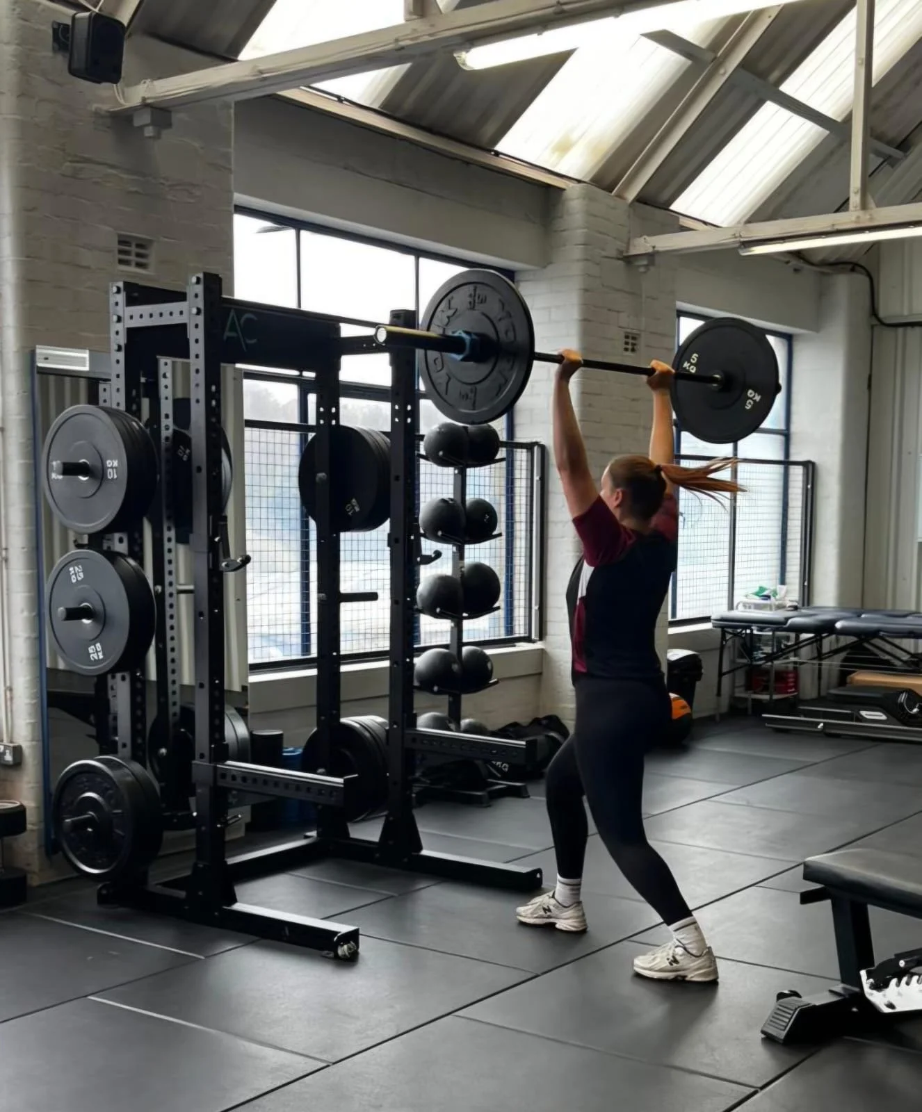 A woman lifting a barbell with weights at a gym.