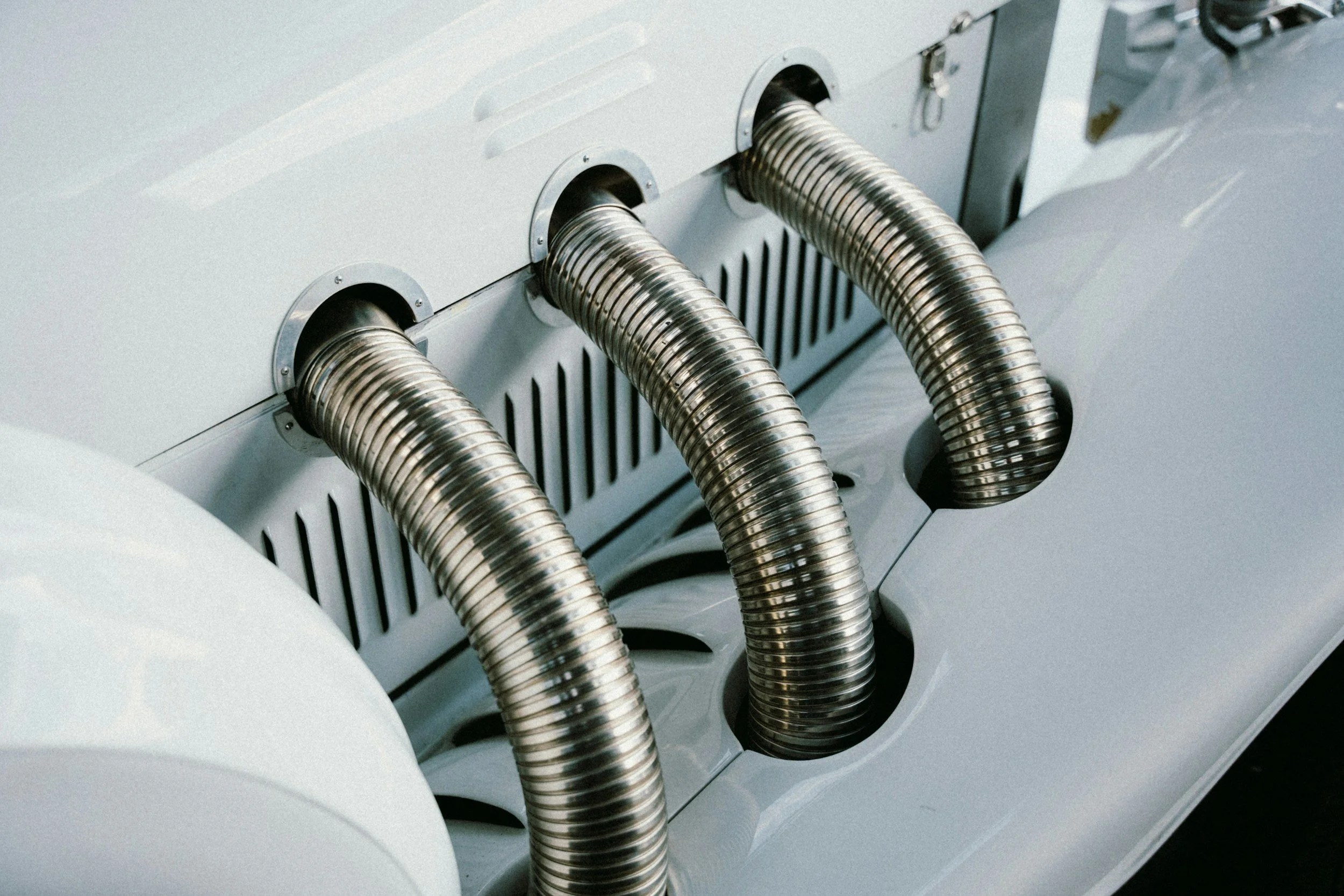 Metalrør forbundet til en maskine, sandsynligvis en industri- eller teknologimaskine.