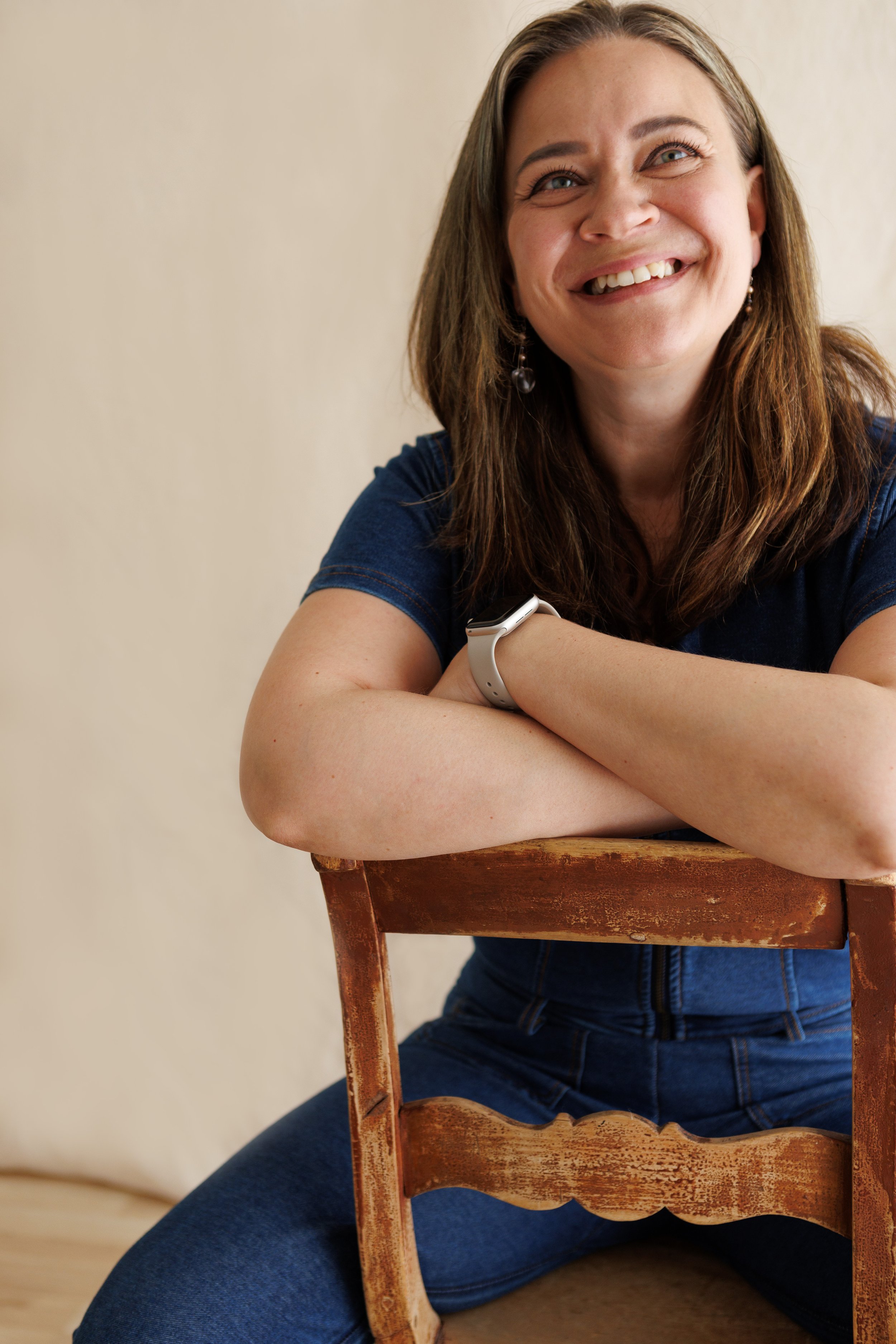Minna Fagerlund istuu tuolilla ja hymyilee