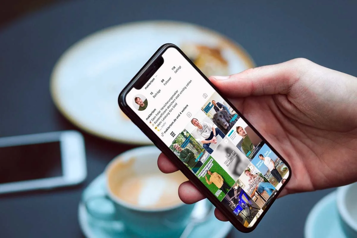 Hand mit iPhone auf dem der Instagram Feed von maklertom zu sehen ist