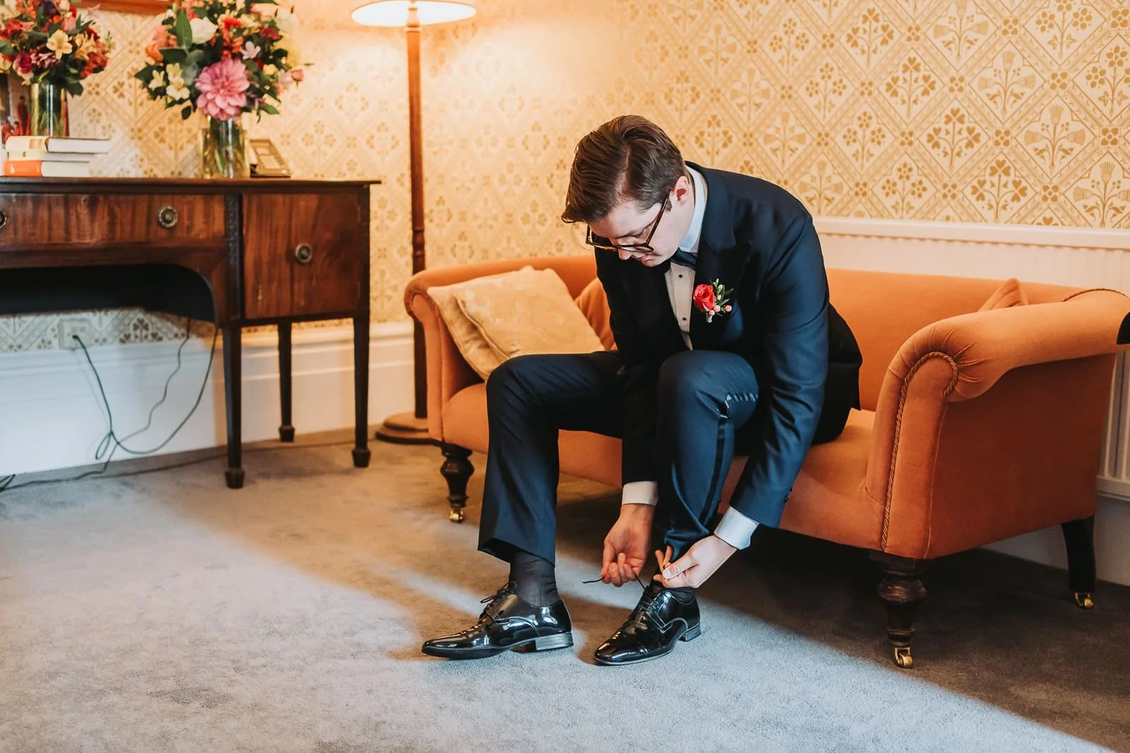 Groom adjusting shoes before wedding ceremony at Magdalen College