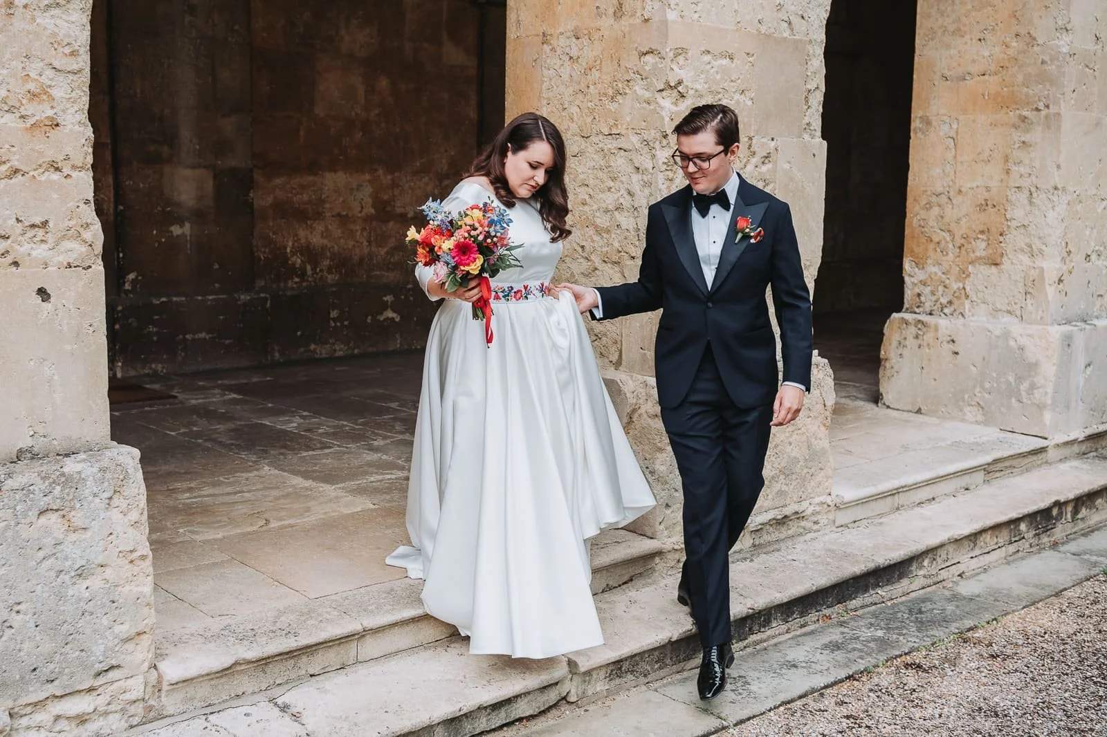 Groom helping bride down the stairs of Magdalen Chapel