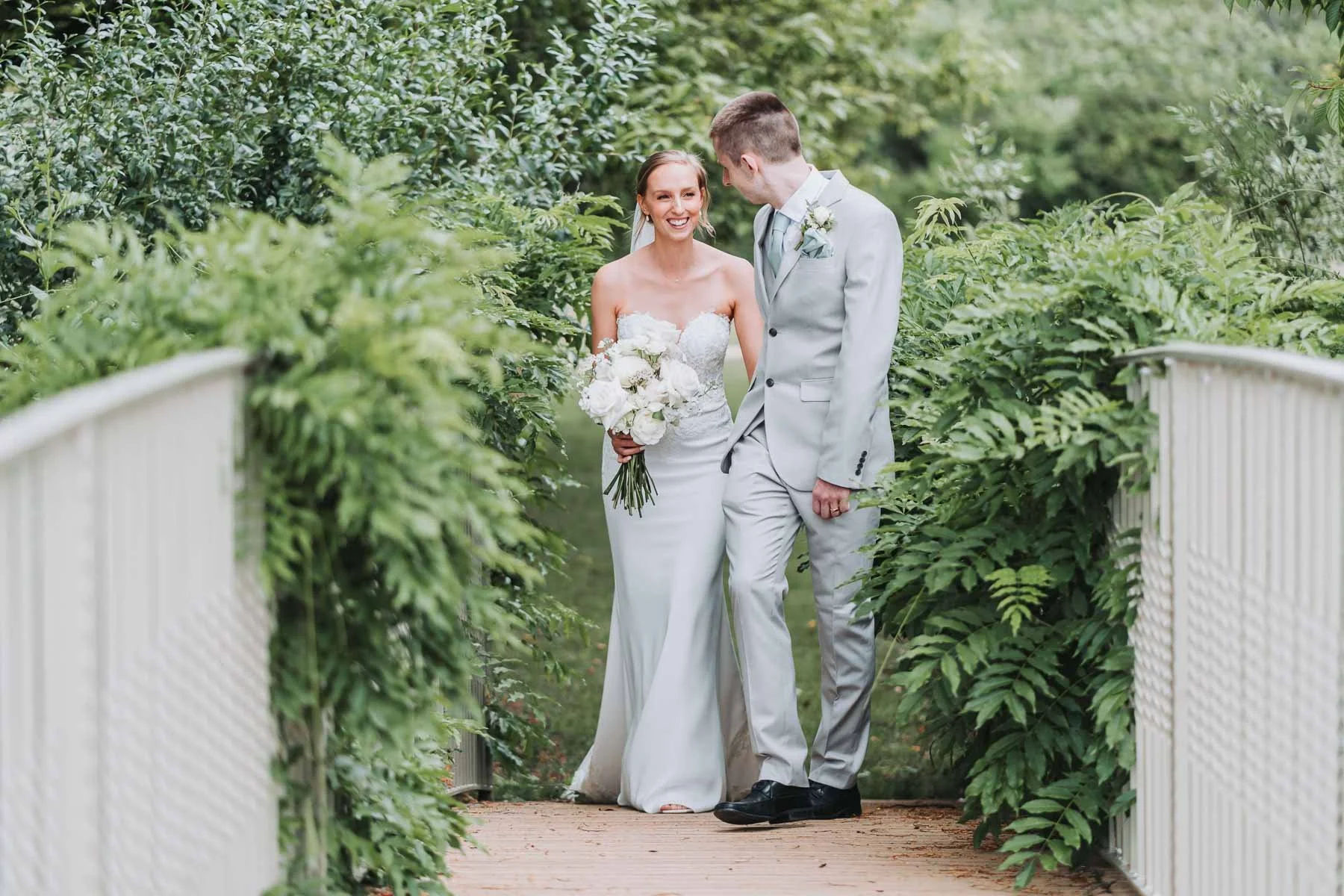 bride-and-groom-walking-over-caswell-house-bridge-oxfordshire-wedding-venue.jpg