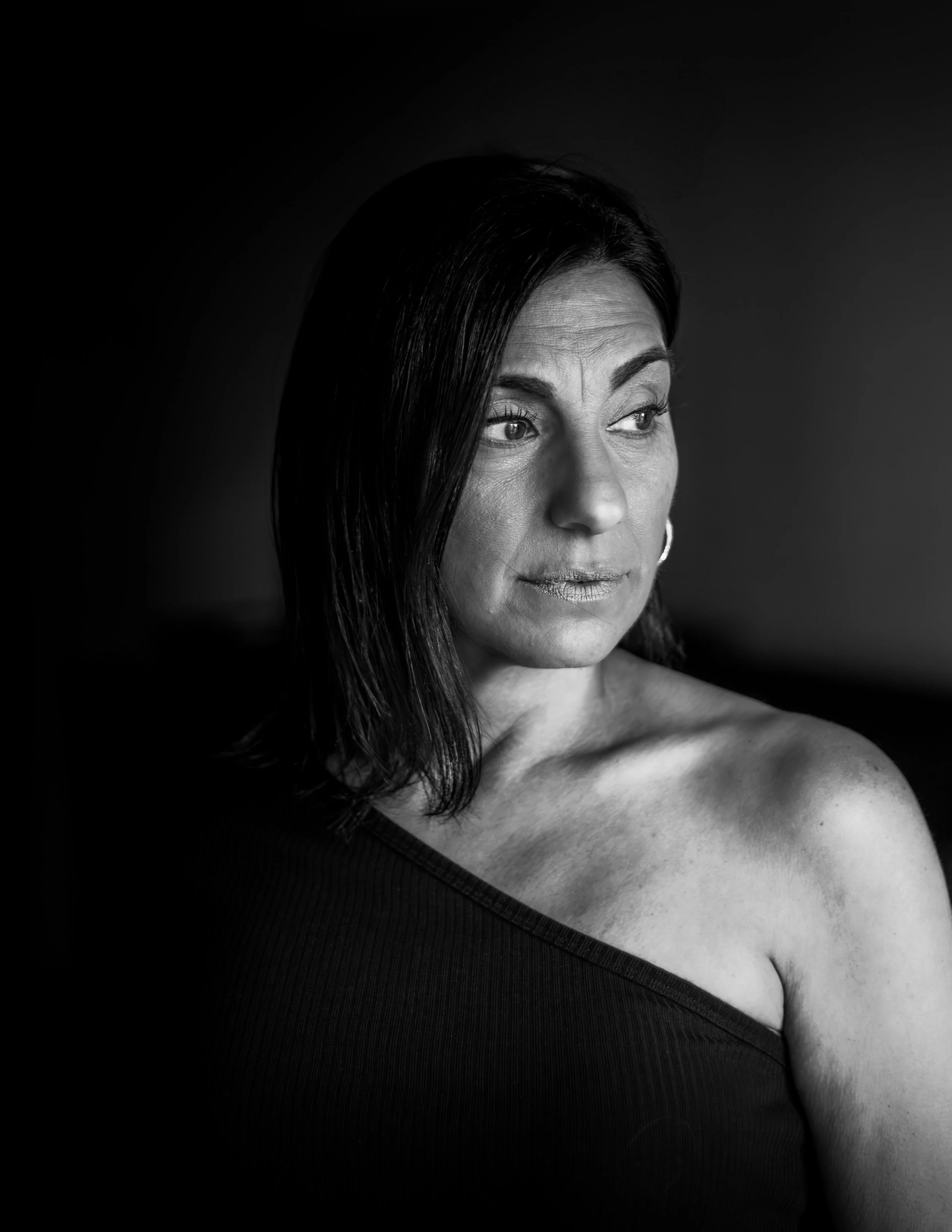 Black and white portrait of a woman with dark hair, looking to the side, with a neutral expression.