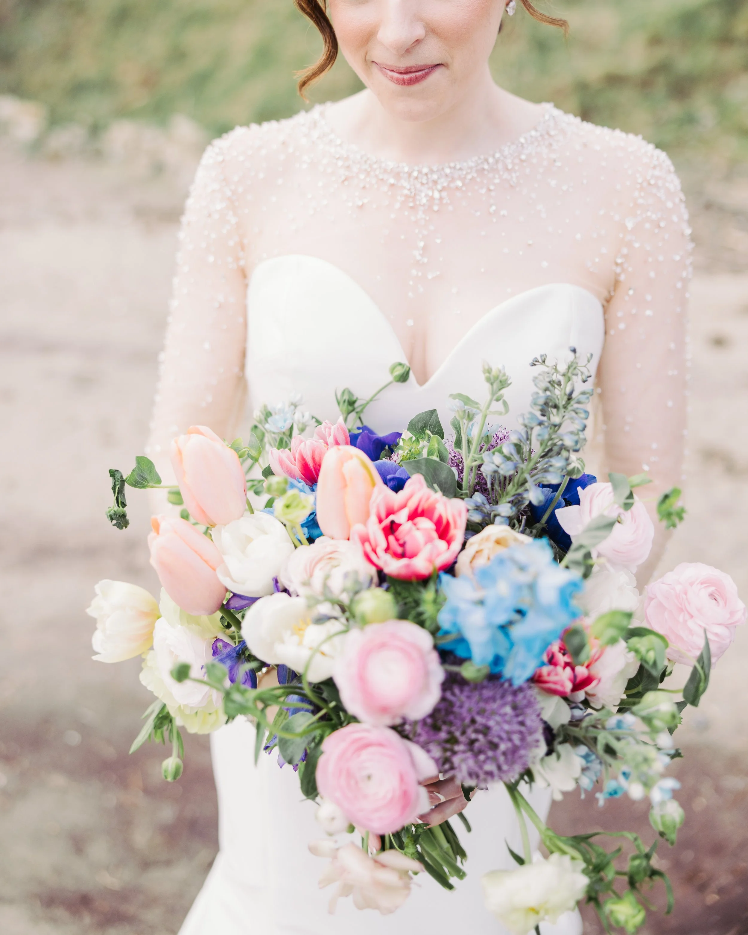 A woman in a wedding dress holding a colorful bouquet of flowers.