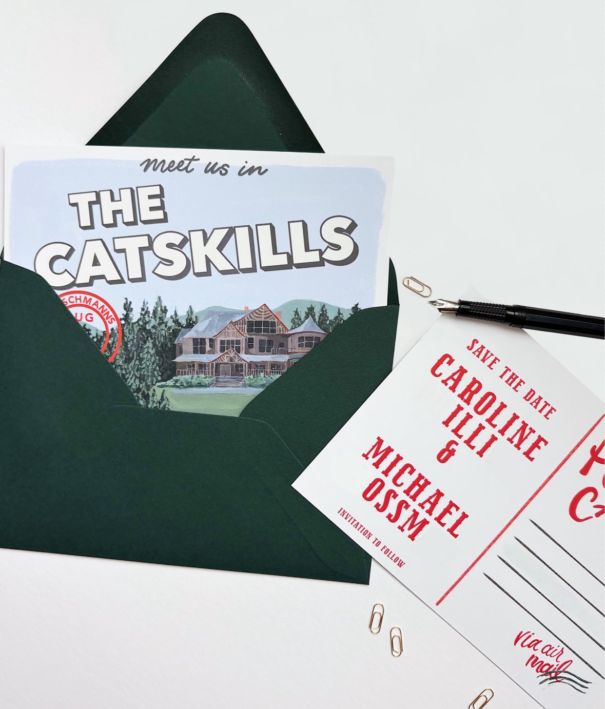 Invitation for a wedding with the names Caroline Lilly and Michael Ossm, a 'Save the Date' card, a pen, paper clips, and a green envelope. The booklet titled 'Meet us in The Catskills' is also visible.