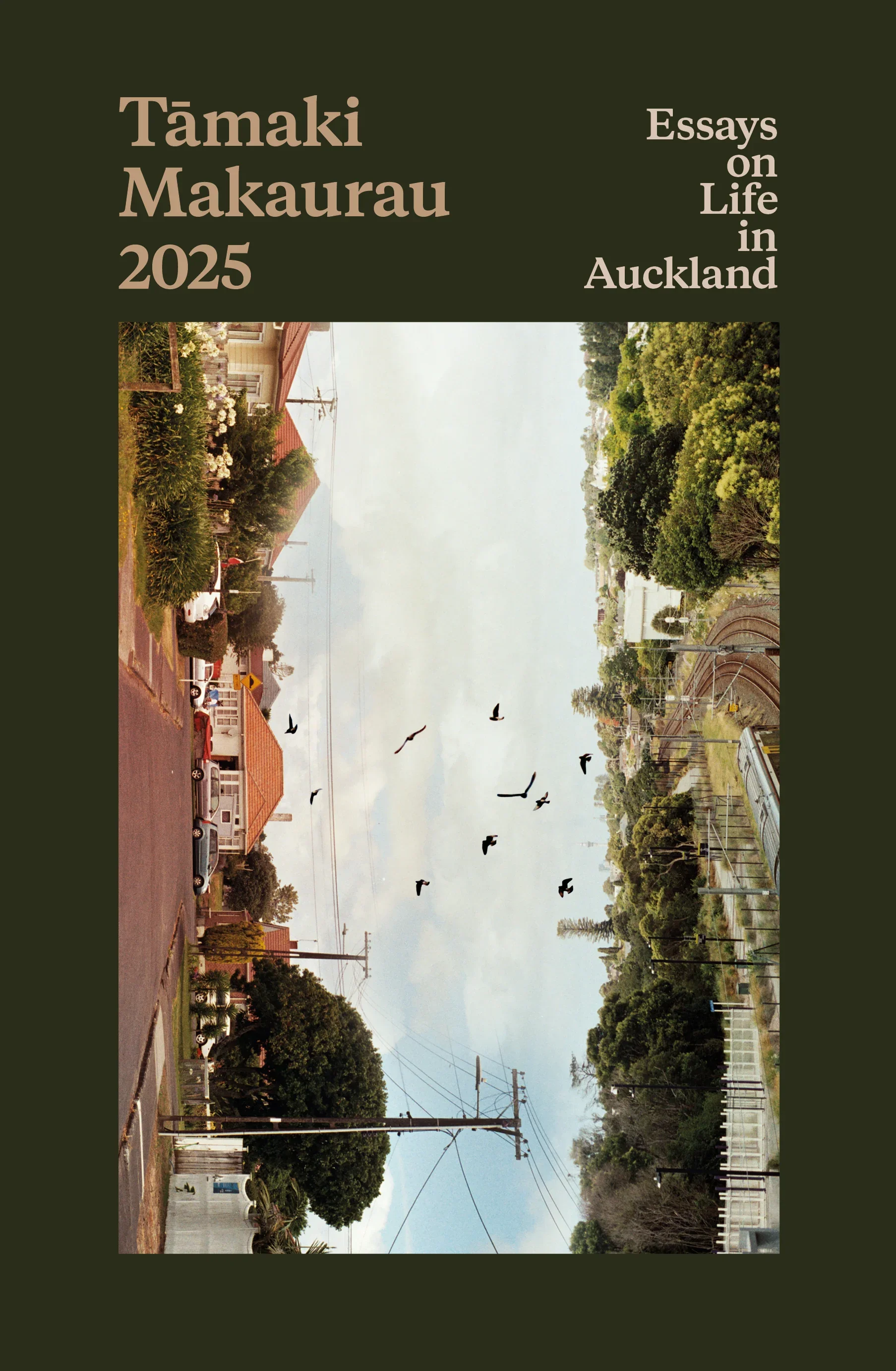Book cover titled 'Tamaki Makaurau 2025: Essays on Life in Auckland' with a photo of an Auckland neighborhood showing houses, trees, power lines, and a flock of birds in the sky.