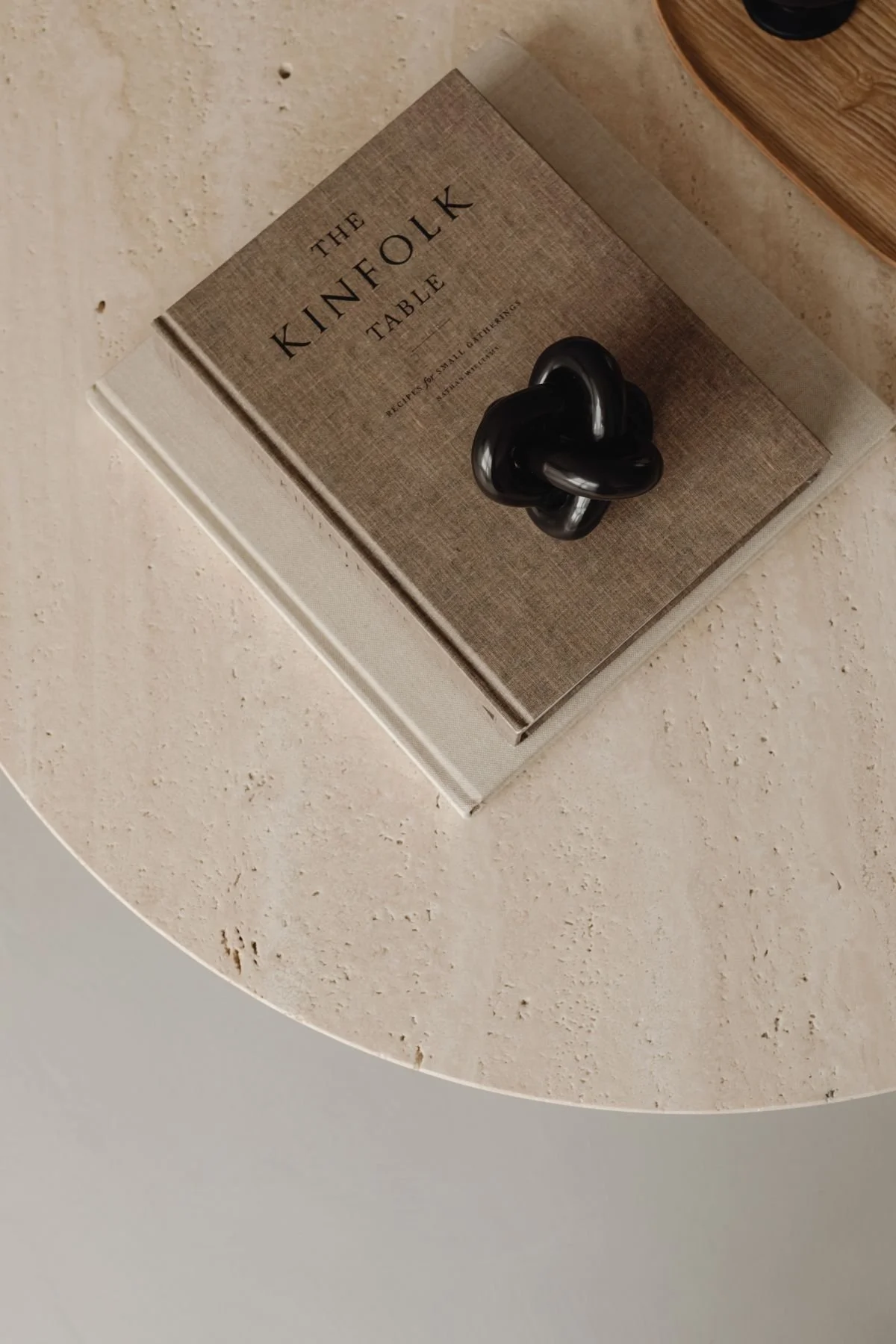 Custom Squarespace Template, E-commerce Squarespace Template, Avelã Creative. A book titled "The Kinfolk Table" resting on a beige textured tabletop with a black decorative knot sculpture placed on top.